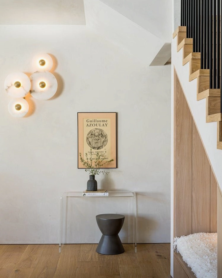 Beran alabaster wall lamp mounted in home entryway corner by stairwell, cascading four-head design creating warm sculptural lighting accent in transitional interior