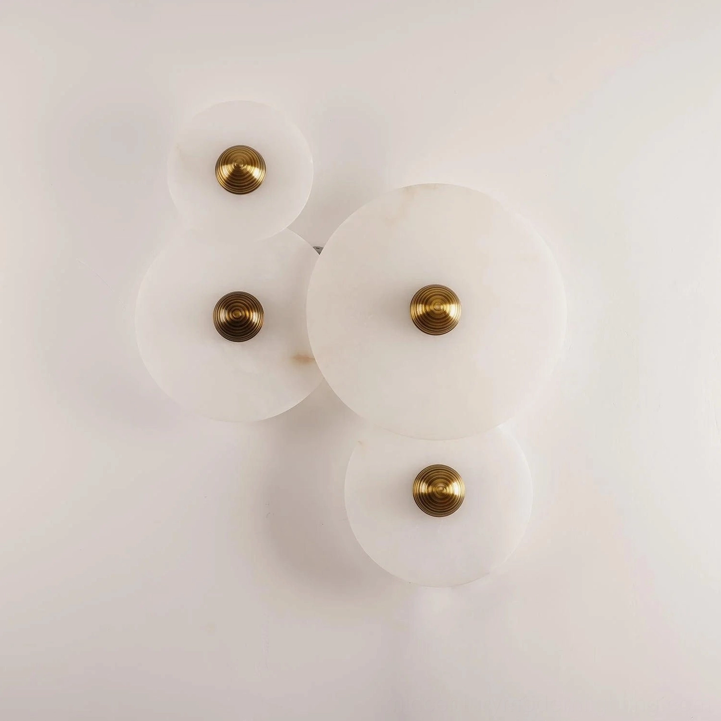 Overhead studio view of Beran alabaster wall lamp, four-head cascading cluster with polished brass fixtures, natural white alabaster stone material, unlit product photography