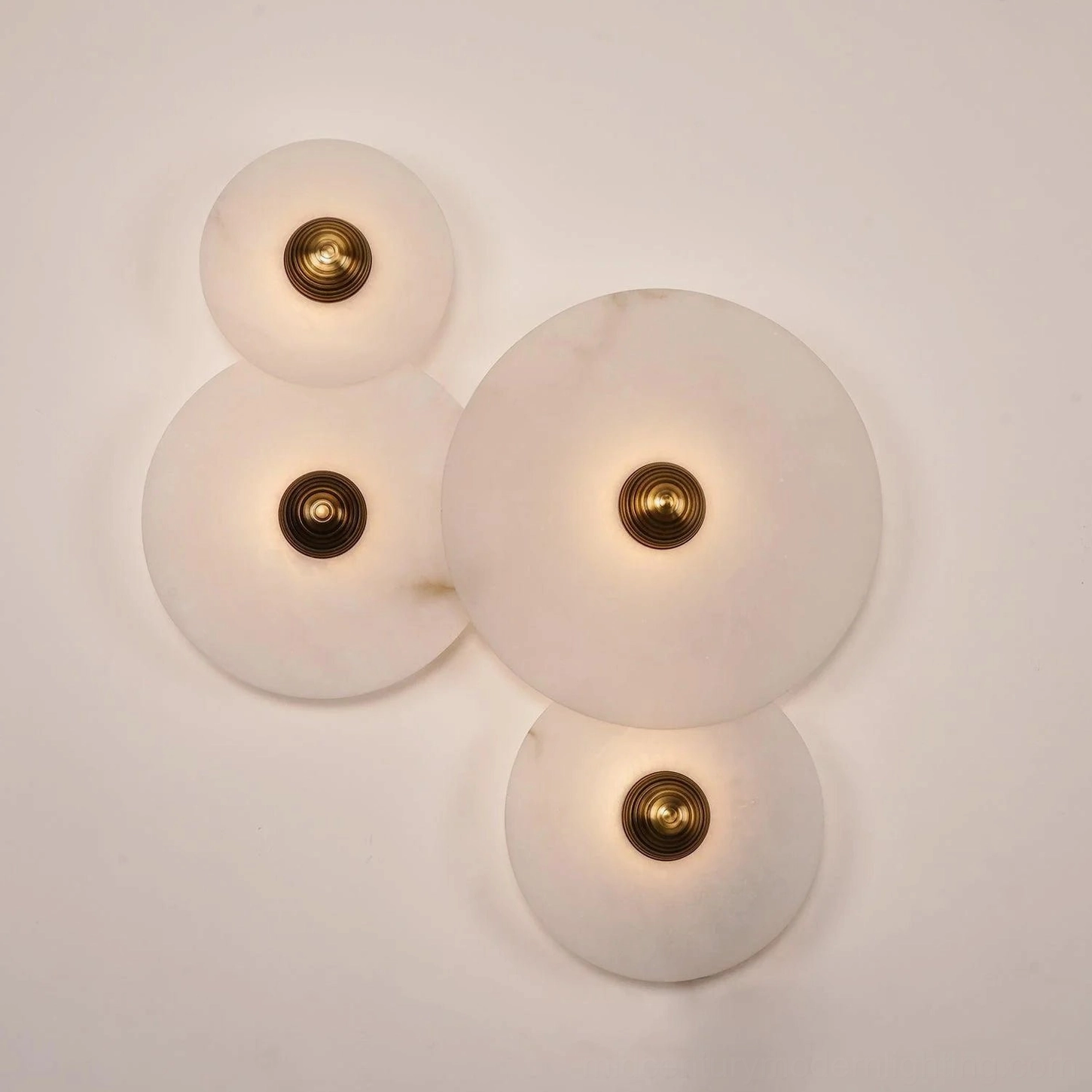 Unlit Beran alabaster wall lamp showing mixed-size translucent alabaster discs, natural stone texture and veining, gold brass accents, studio close-up photography