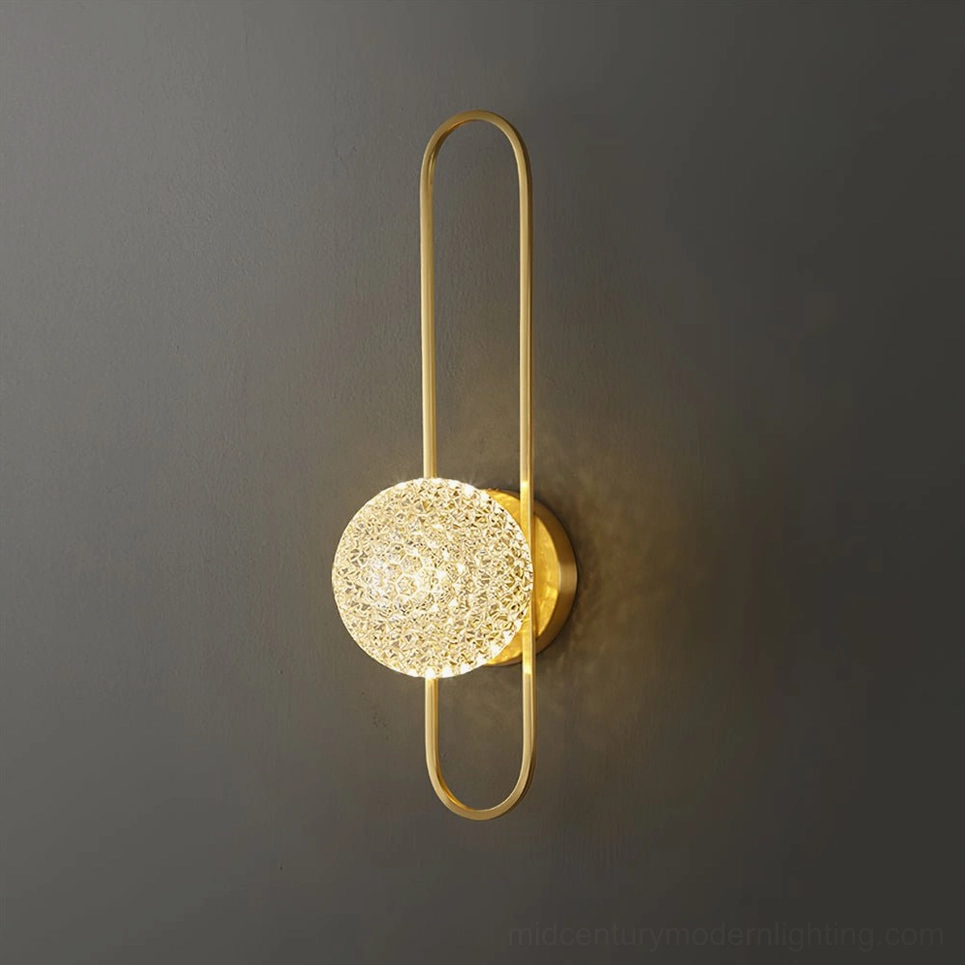 Close-up of Bervalo gold brass wall sconce with textured faceted crystal shade, sleek minimalist design