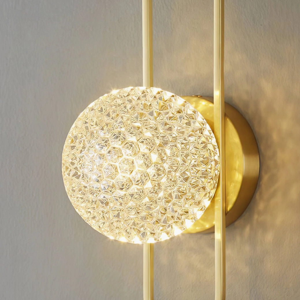 Textured clear crystal shade of Bervalo wall lamp with polished brass hardware detail