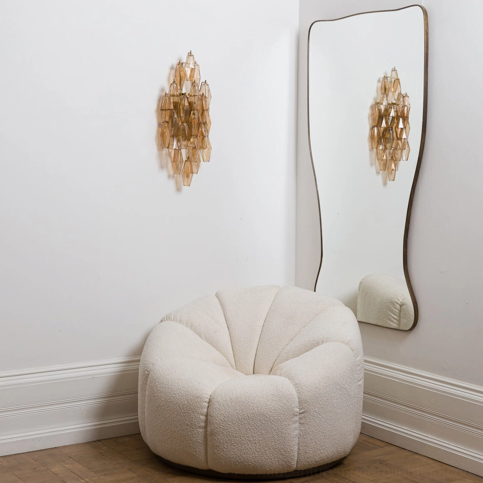 Amber and gold polyhedral glass sconce creating warm luminous effect in corner of minimalist modern room