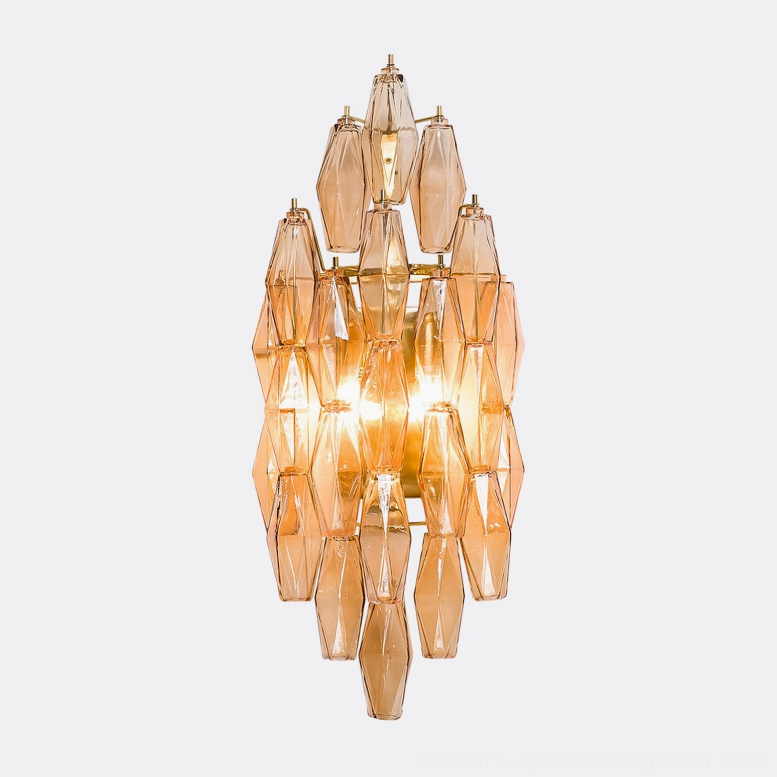 Polyhedral glass sconce illuminated showing warm light through geometric glass facets