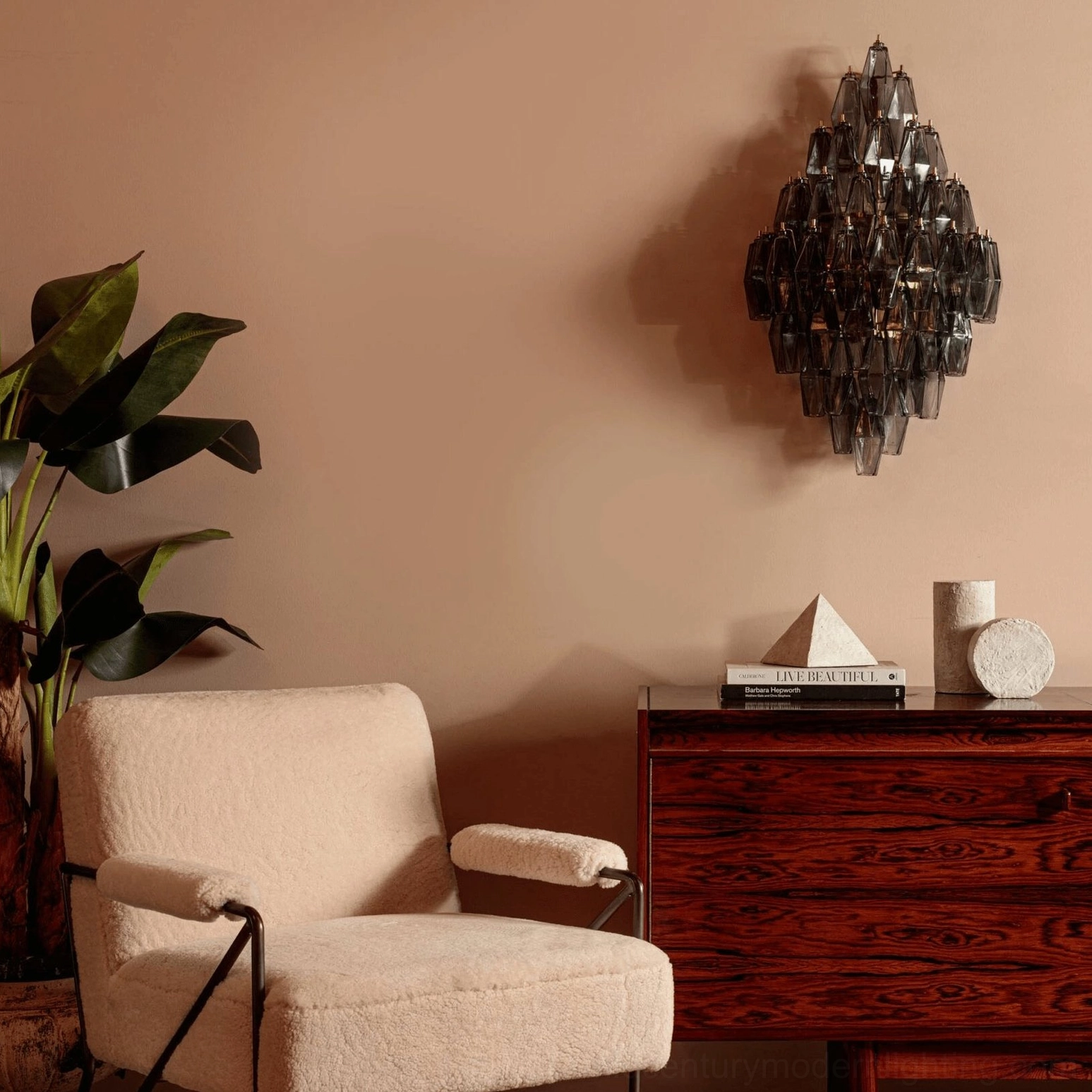 Dark smoky grey polyhedral glass sconce installed in minimalist living room with modern décor and boucle chair
