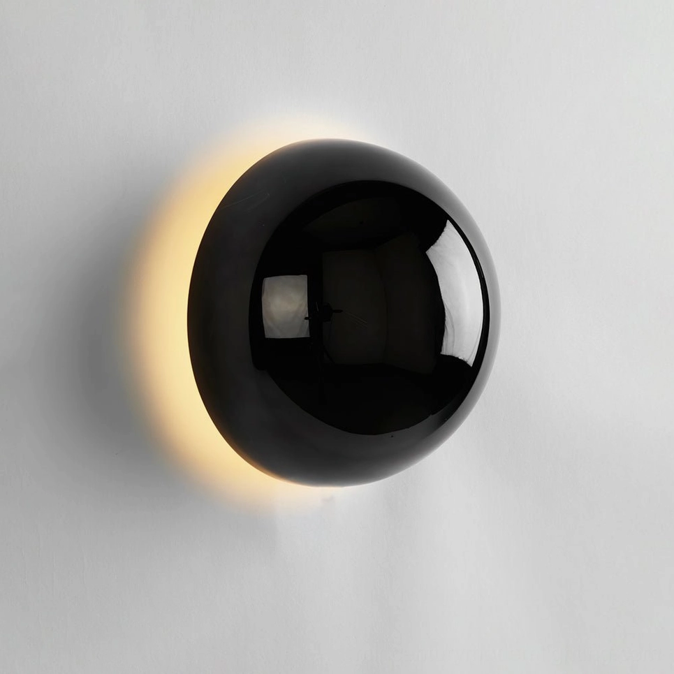 Matte black adjustable sphere wall sconce in industrial modern bedroom setting