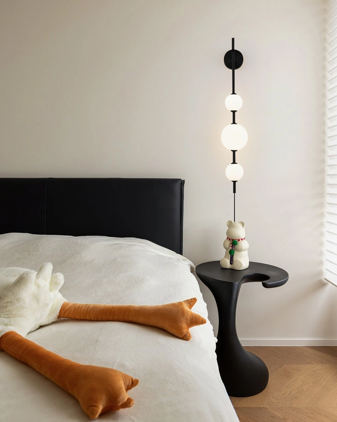 Black vertical globe wall lamp with frosted spheres in contemporary master bedroom beside bed