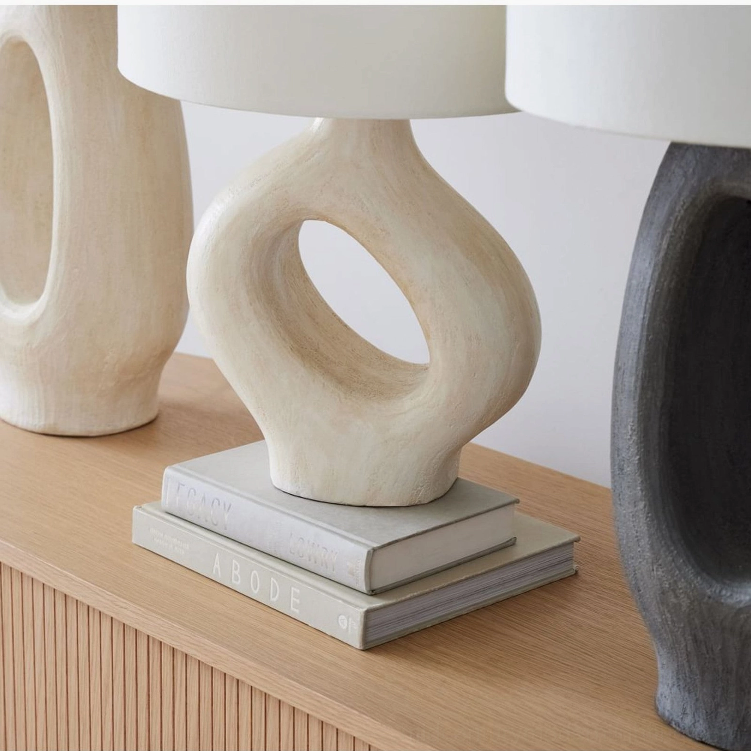 Sauce sculptural table lamp with black resin cutout base and white fabric shade, three-quarter angle view