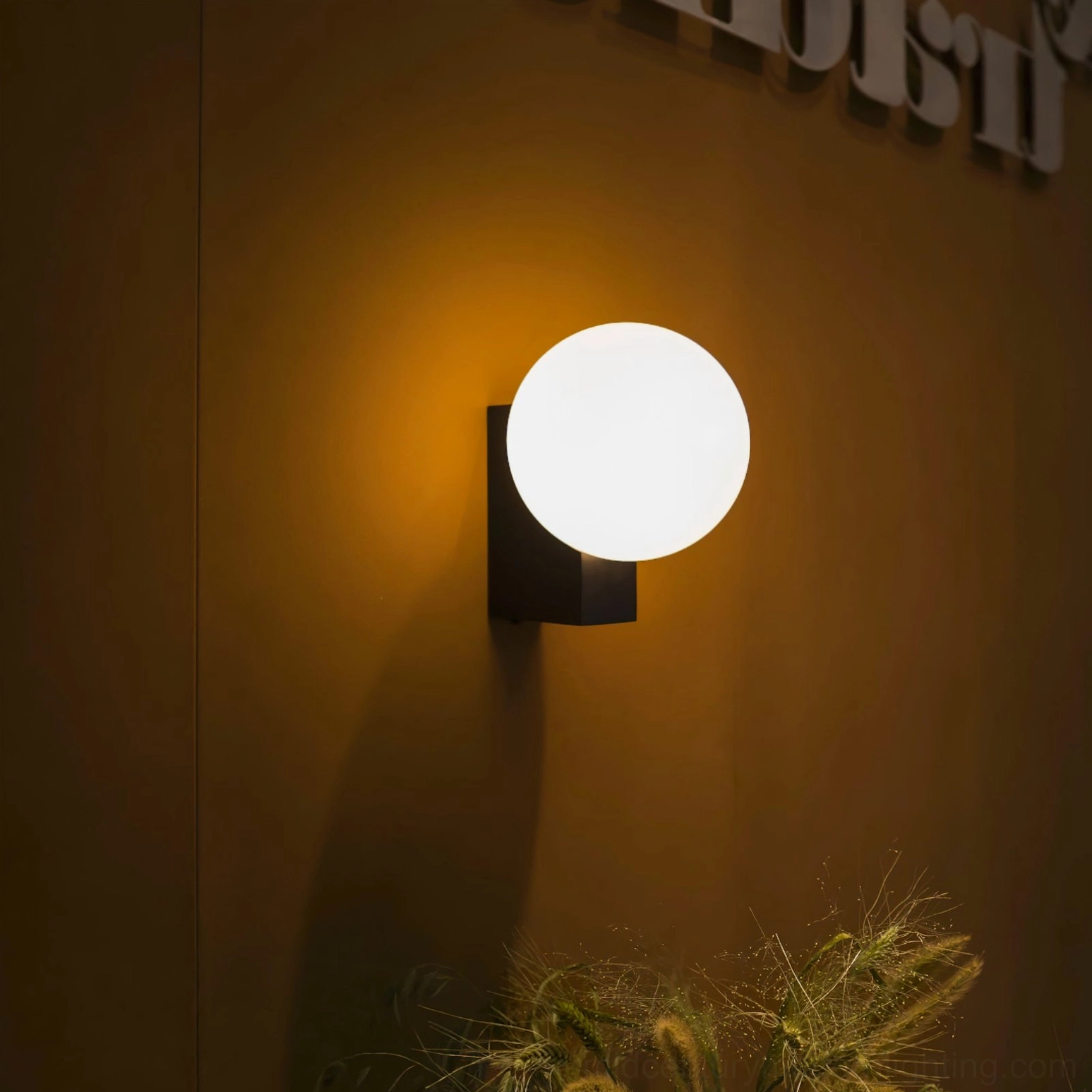 Modern minimalist wall light with frosted glass globe against warm amber accent wall in contemporary home design