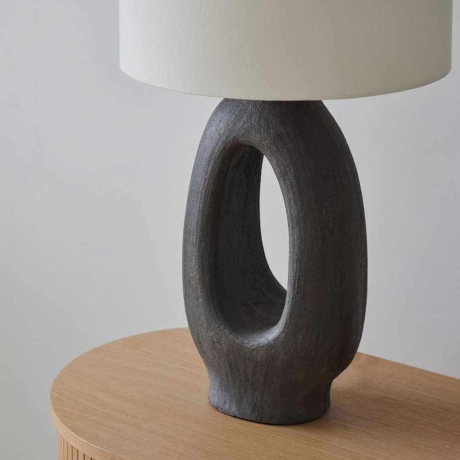 Black sculptural resin table lamp with white fabric shade, graphic contemporary interior styling