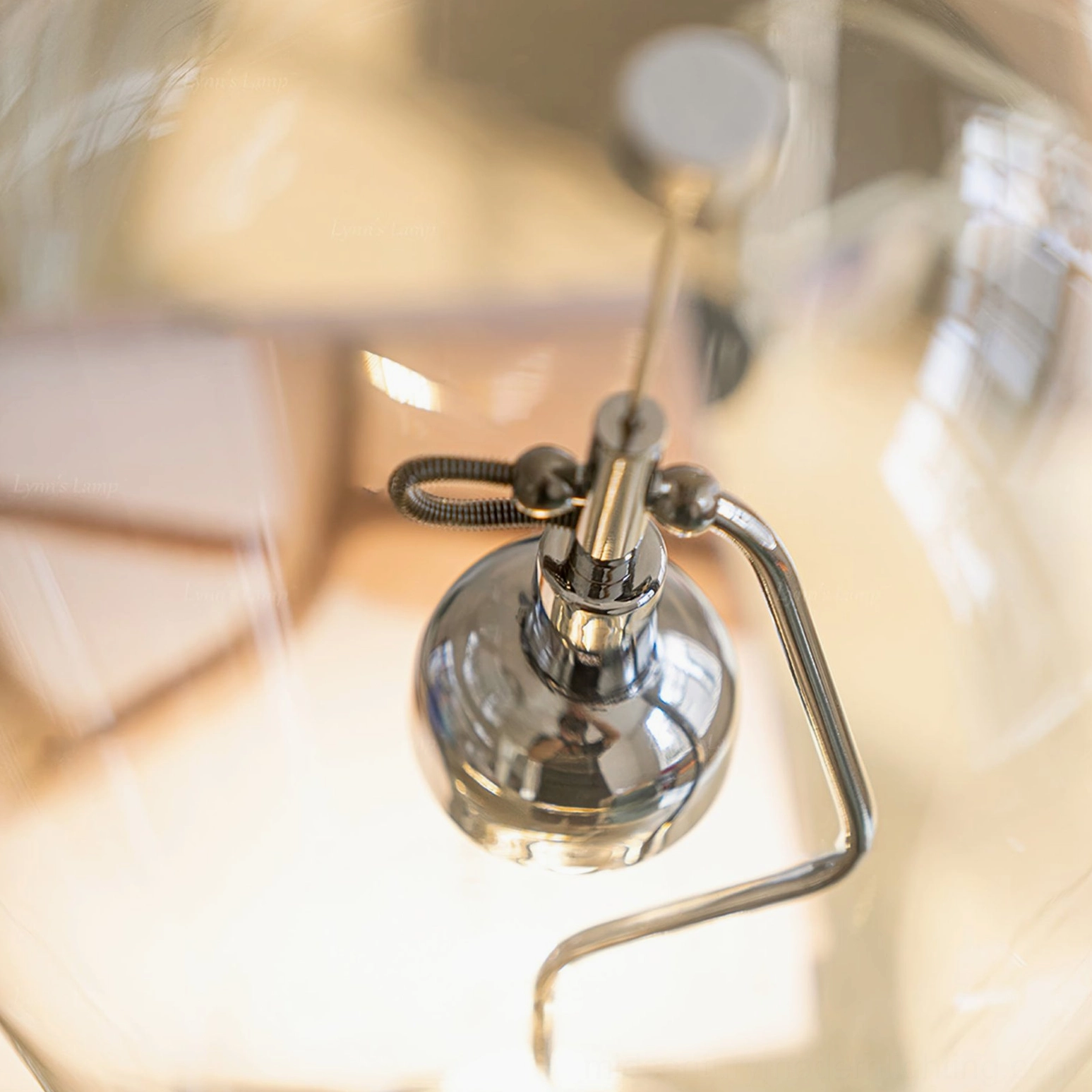 Blow table lamp internal structure macro view showing curved polished chrome metal arm and fixtures