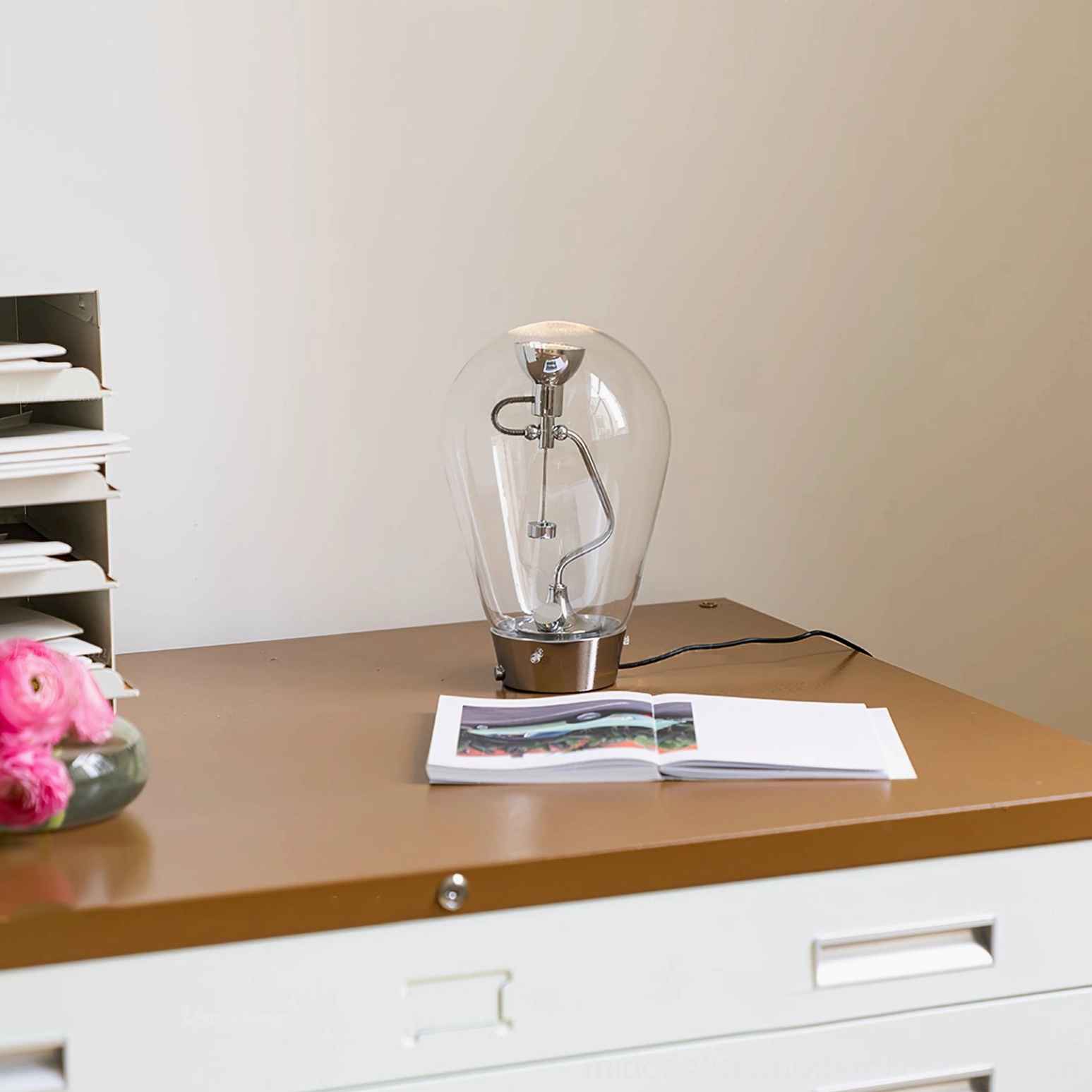 Blow clear glass lamp side profile showing chrome metal arm and glass shade detail on office desk