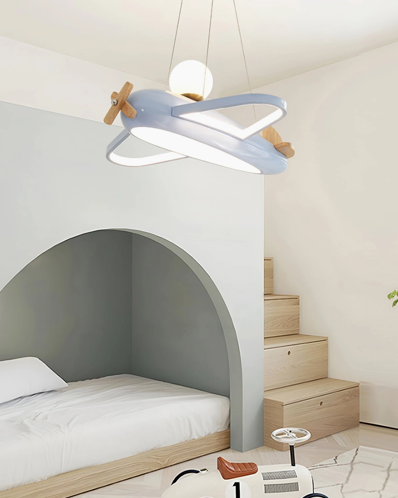 Blue aircraft pendant lamp in small kids bedroom with arch bed and wooden accents