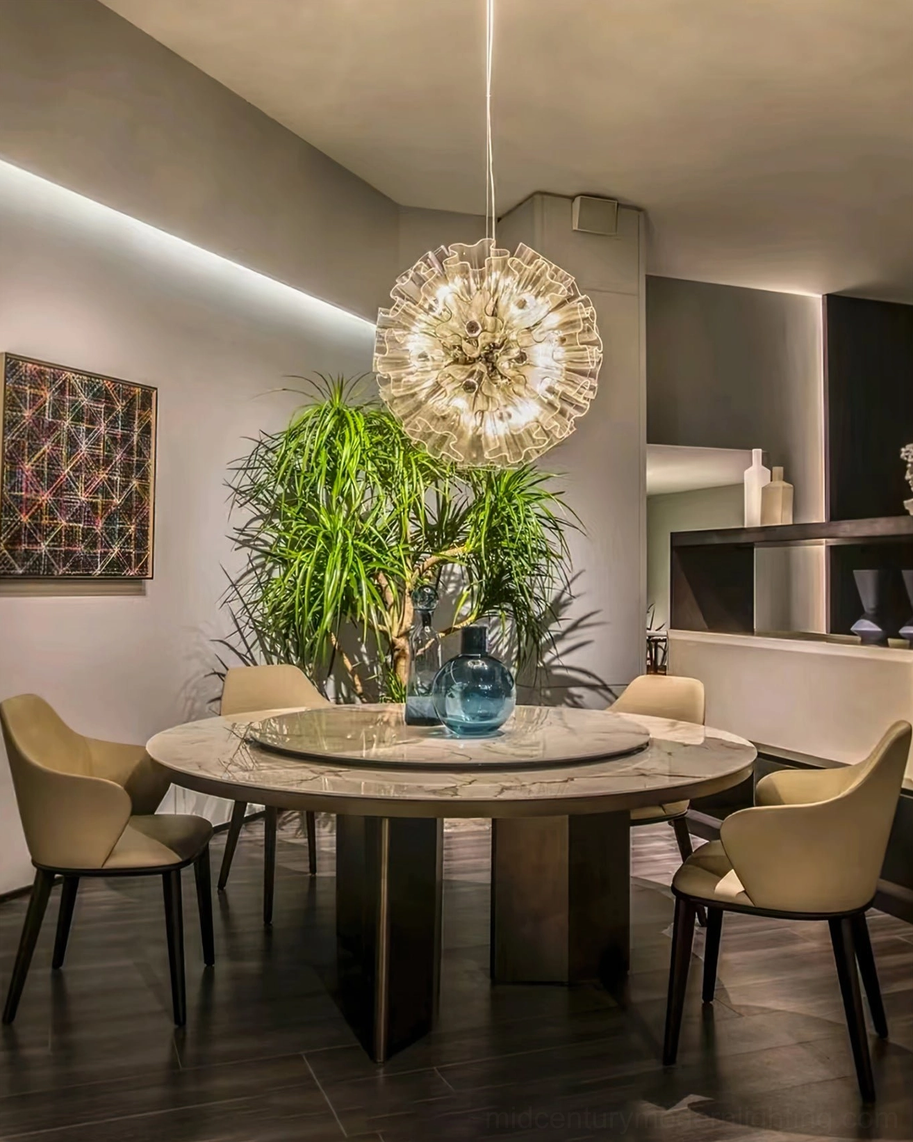 Blum Chandelier hanging above round dining table in modern dining room with plants and warm lighting