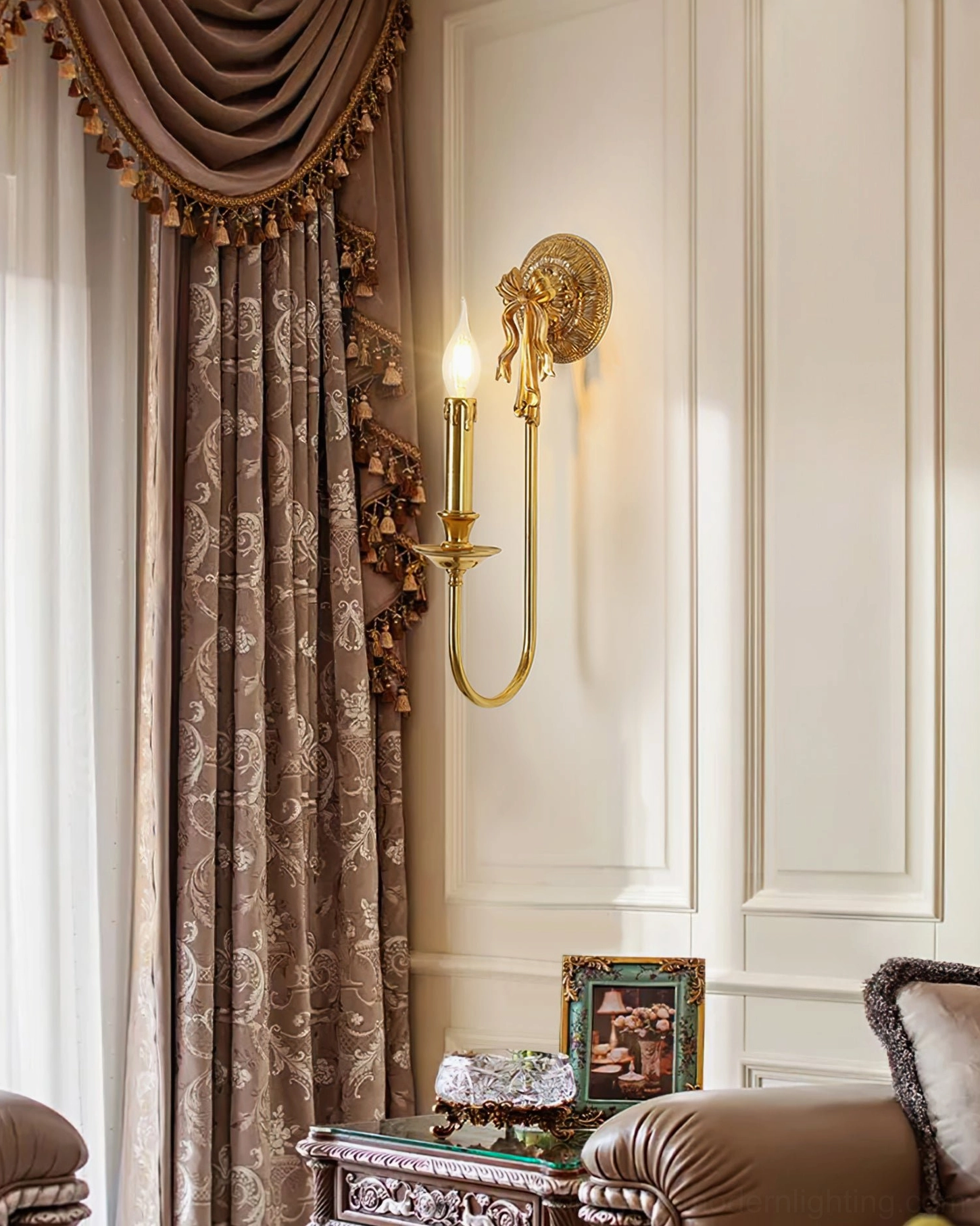Bow brass wall sconce in luxury living room setting with patterned curtains and sofa