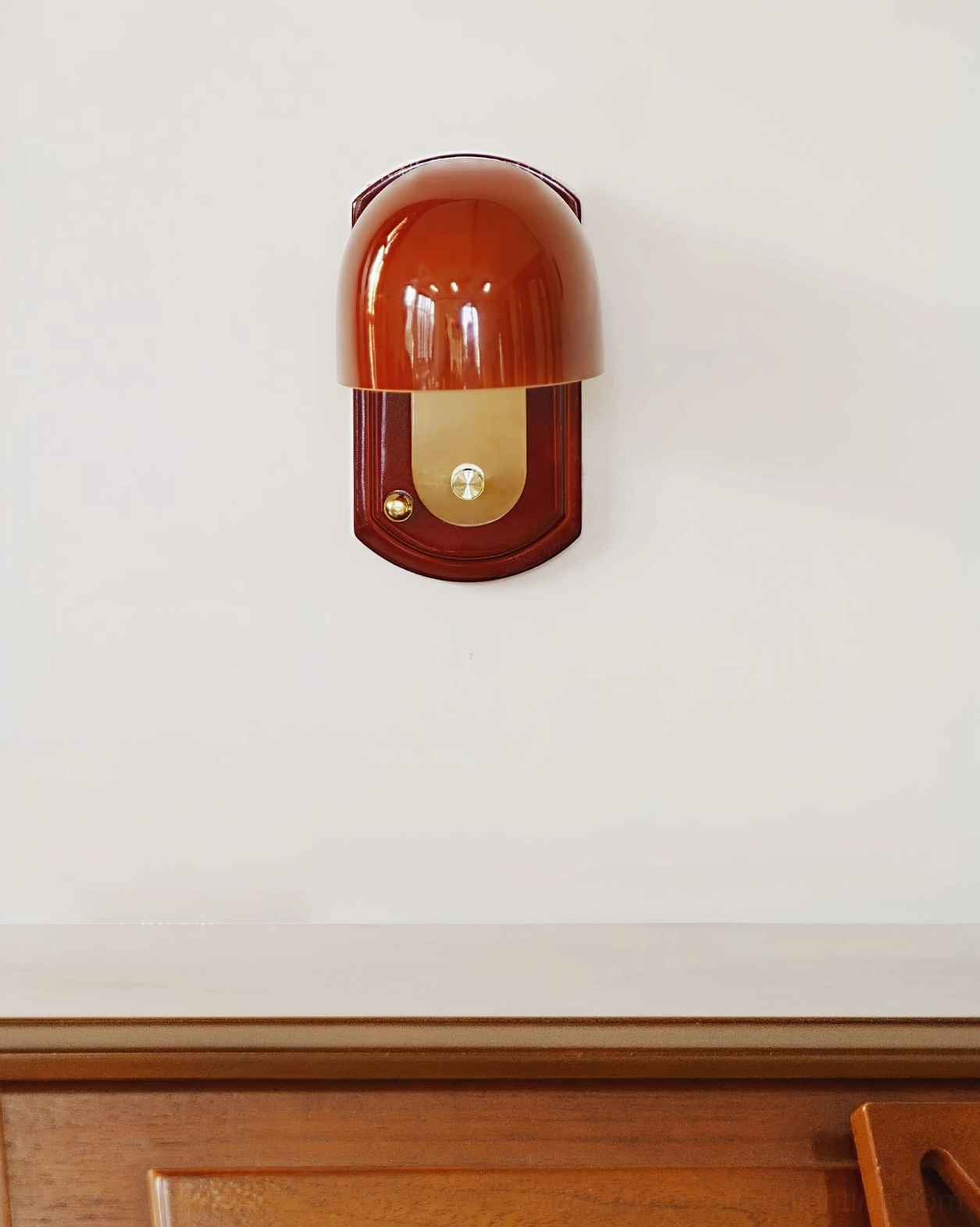 Bradley wall lamp mounted on white interior wall with wood trim showing reddish-brown solid shade and rectangular wood backplate