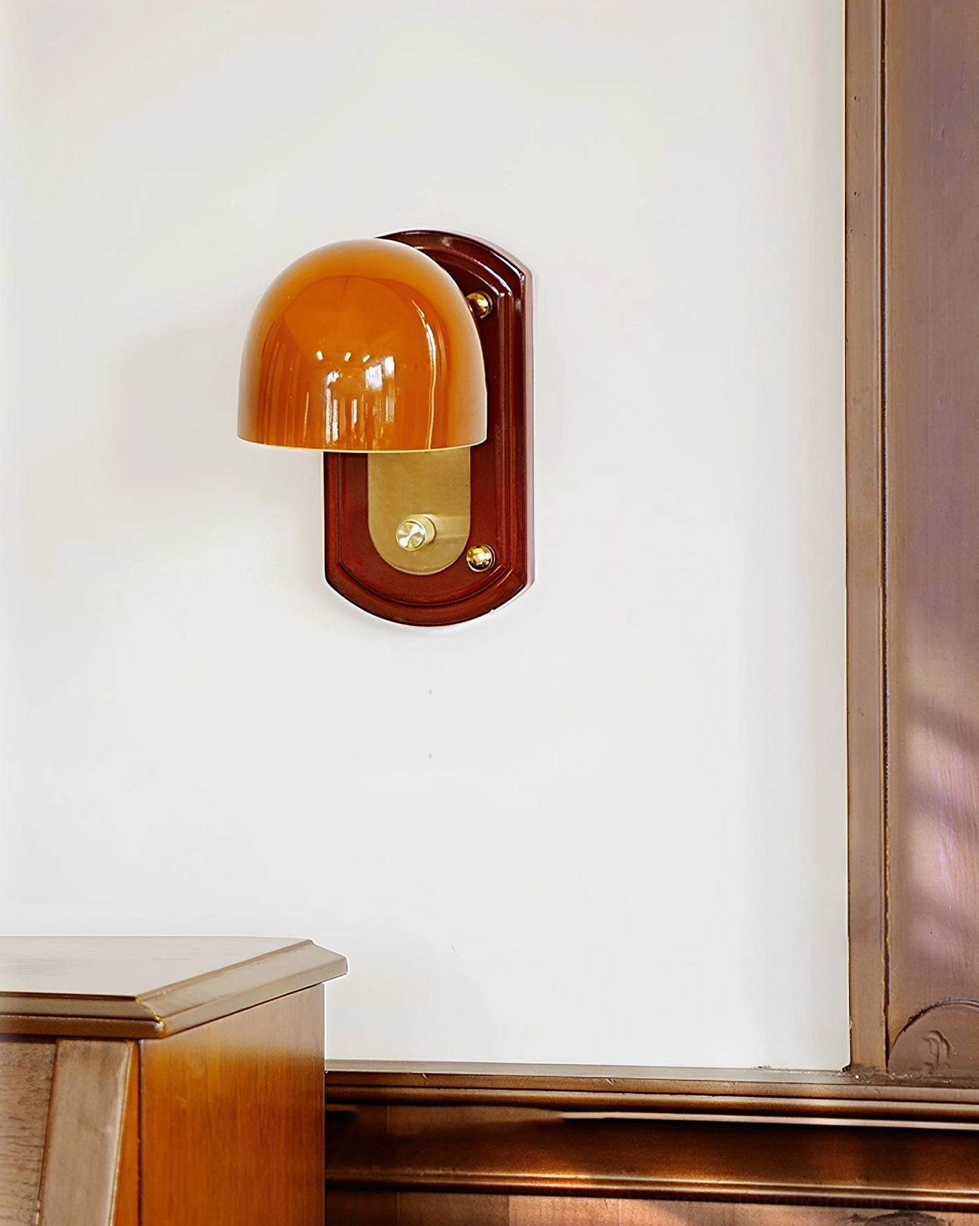 Bradley vintage-inspired wall sconce positioned beside wooden furniture showing compact size and warm amber glow
