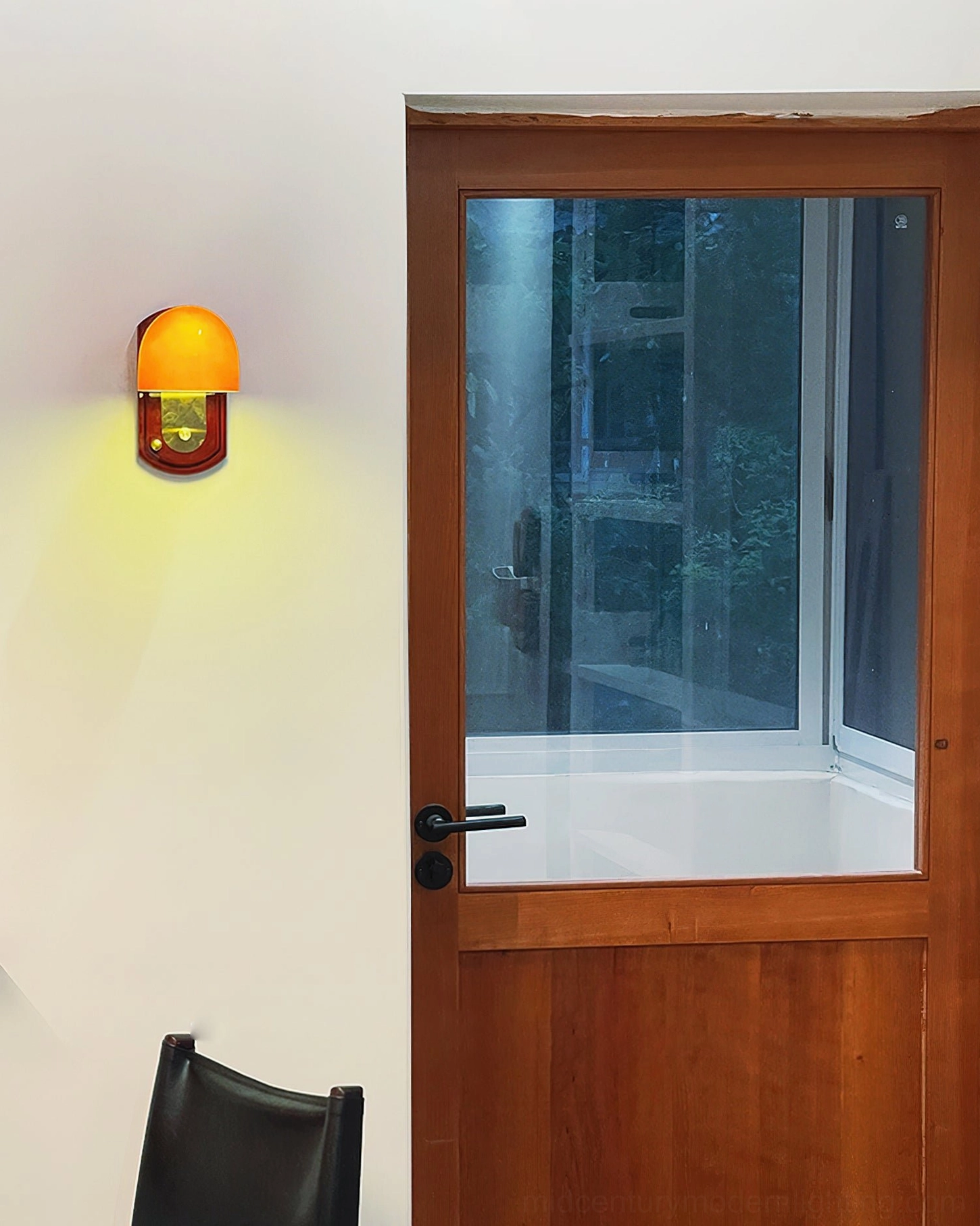 Lit Bradley wall sconce creating warm ambient glow in entryway beside wooden door with brass-wood mount visible