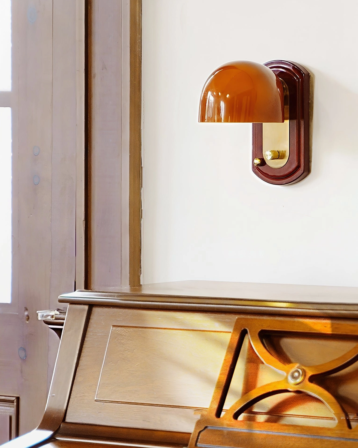 Side profile of Bradley retro wall sconce with reddish-brown dome shade mounted next to vintage piano and natural wood trim
