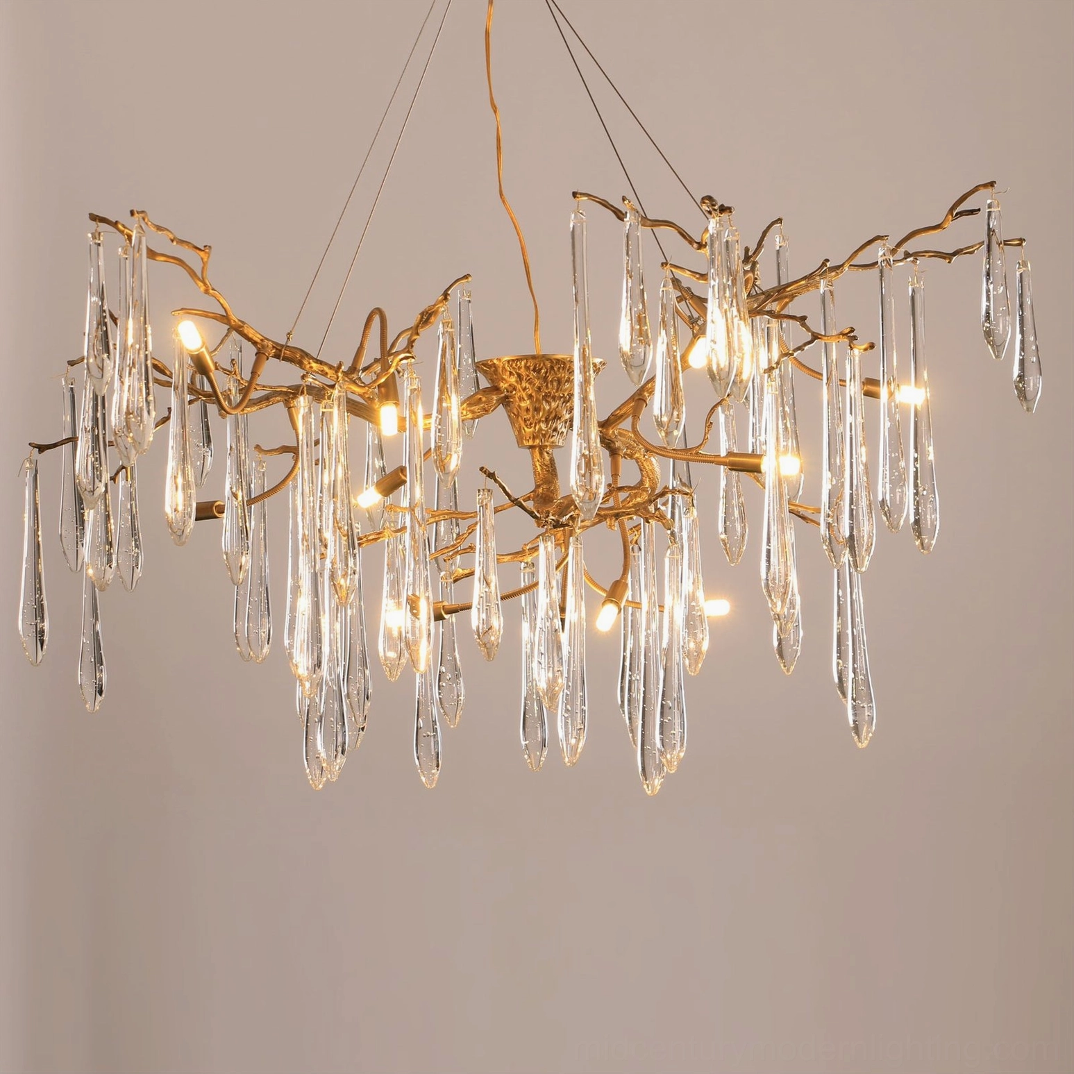Front low-angle view of illuminated Branch Raindrop Chandelier with warm light through Edison bulbs and elegant crystal pendants suspended from brass frame