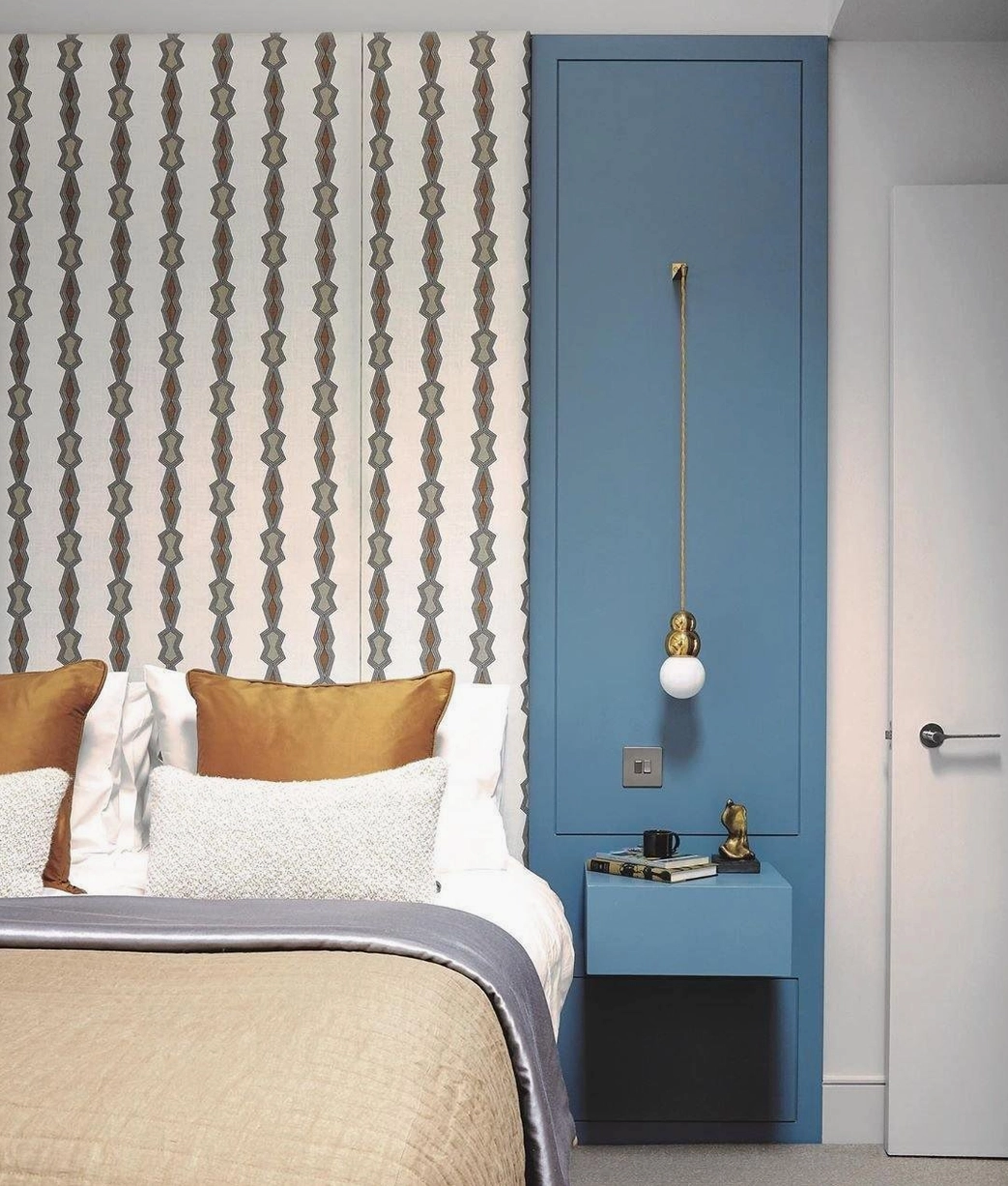 Brass gold ball pendant light in modern bedroom with blue accent wall, warm neutral bedding