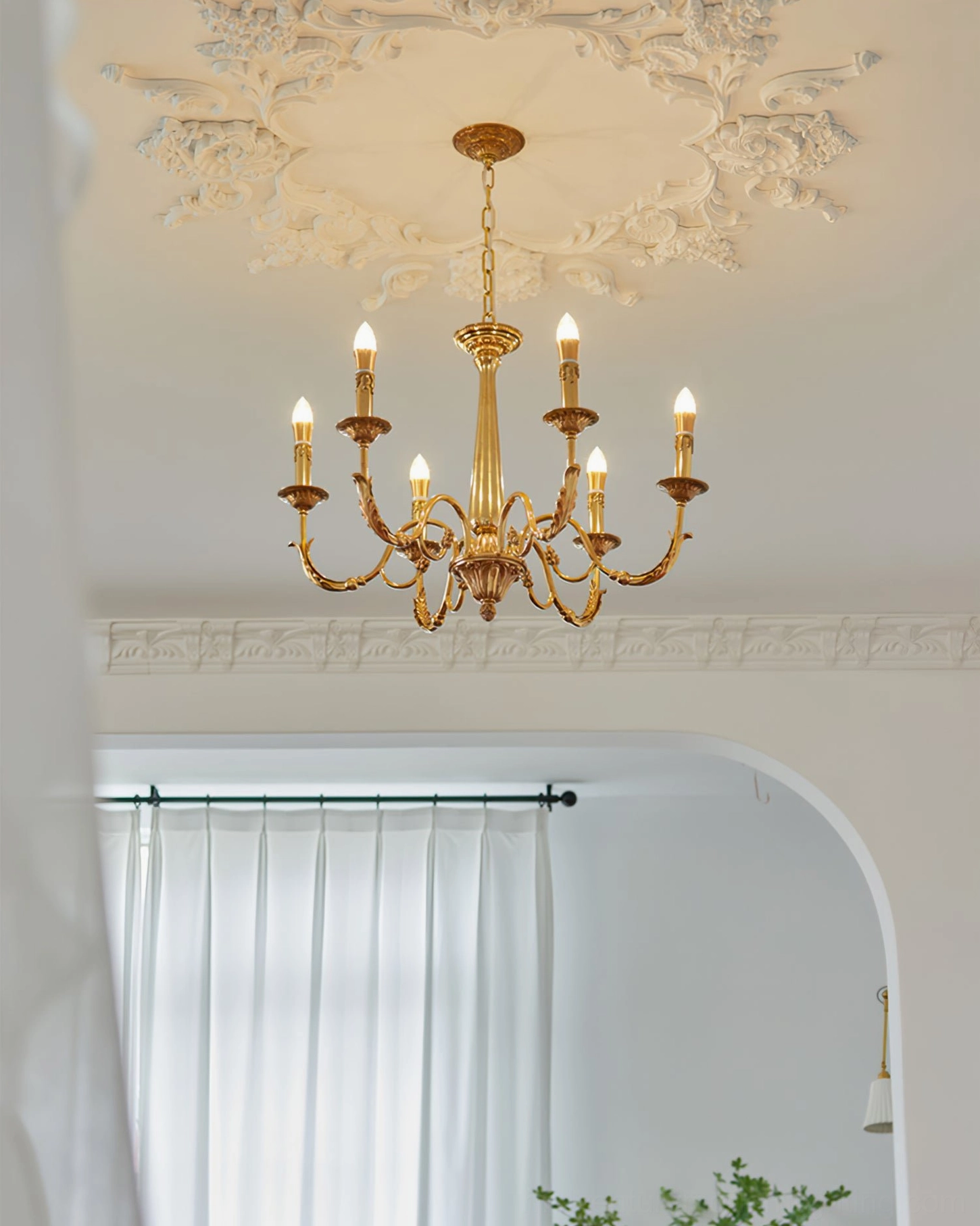Detailed view of brass candle chandelier arms and bulb sockets with ornamental leaf carvings