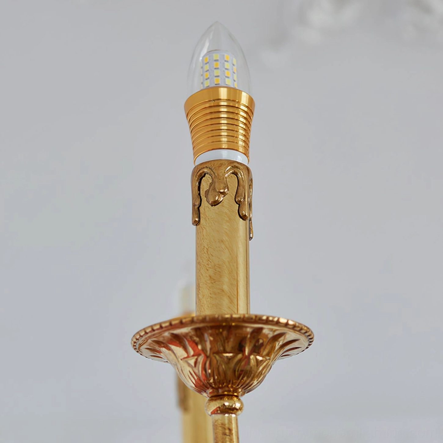 Close-up detail of brass candle socket with carved gold base and decorative metal trim