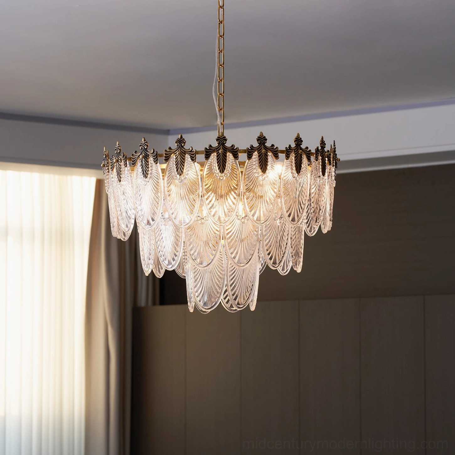 Polished brass tiered chandelier with carved glass leaves in elegant dining room setting, demonstrating warm diffused lighting