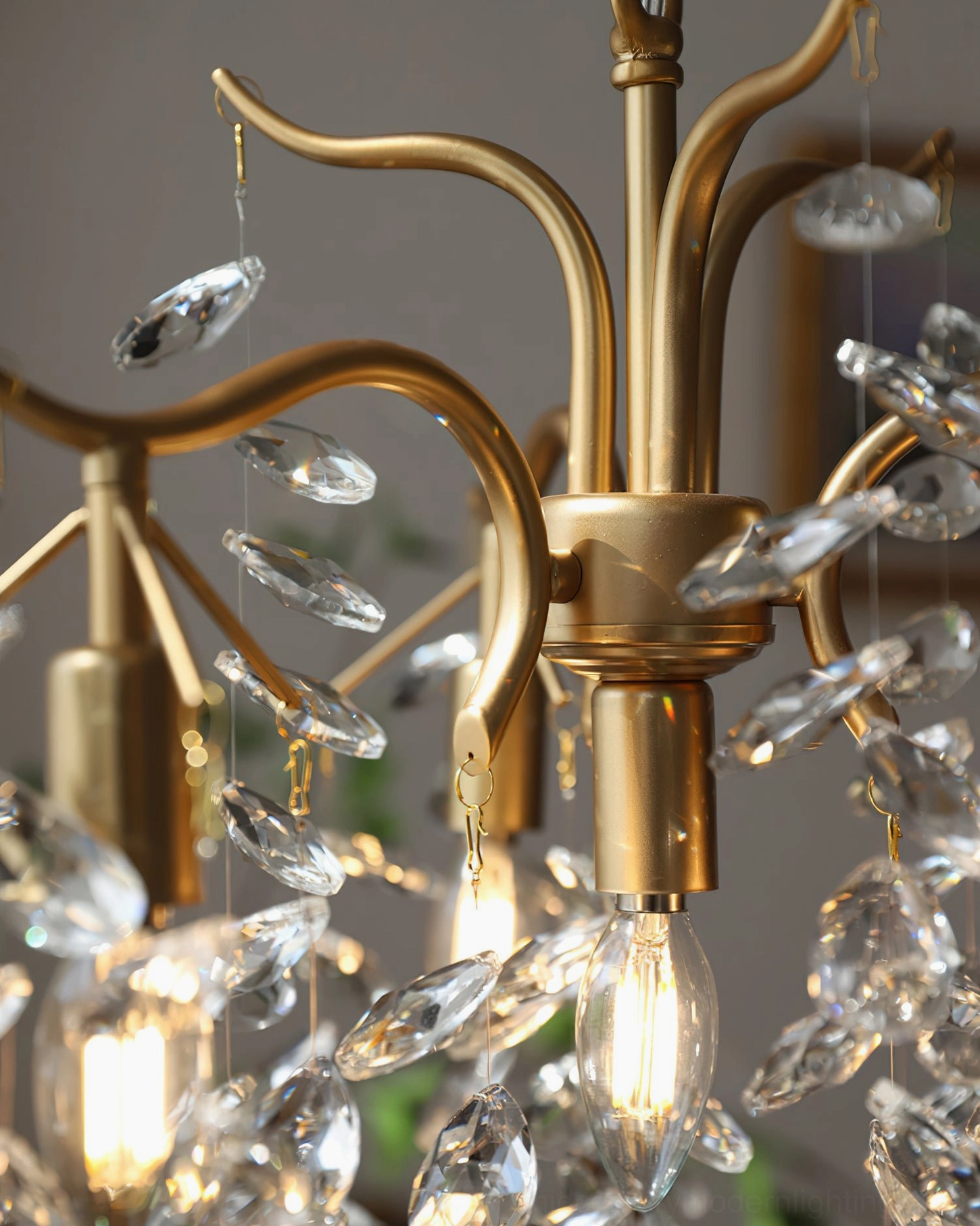 Brass chandelier metal frame close-up from below angle showing polished gold arms and hanging clear crystal leaf droplets
