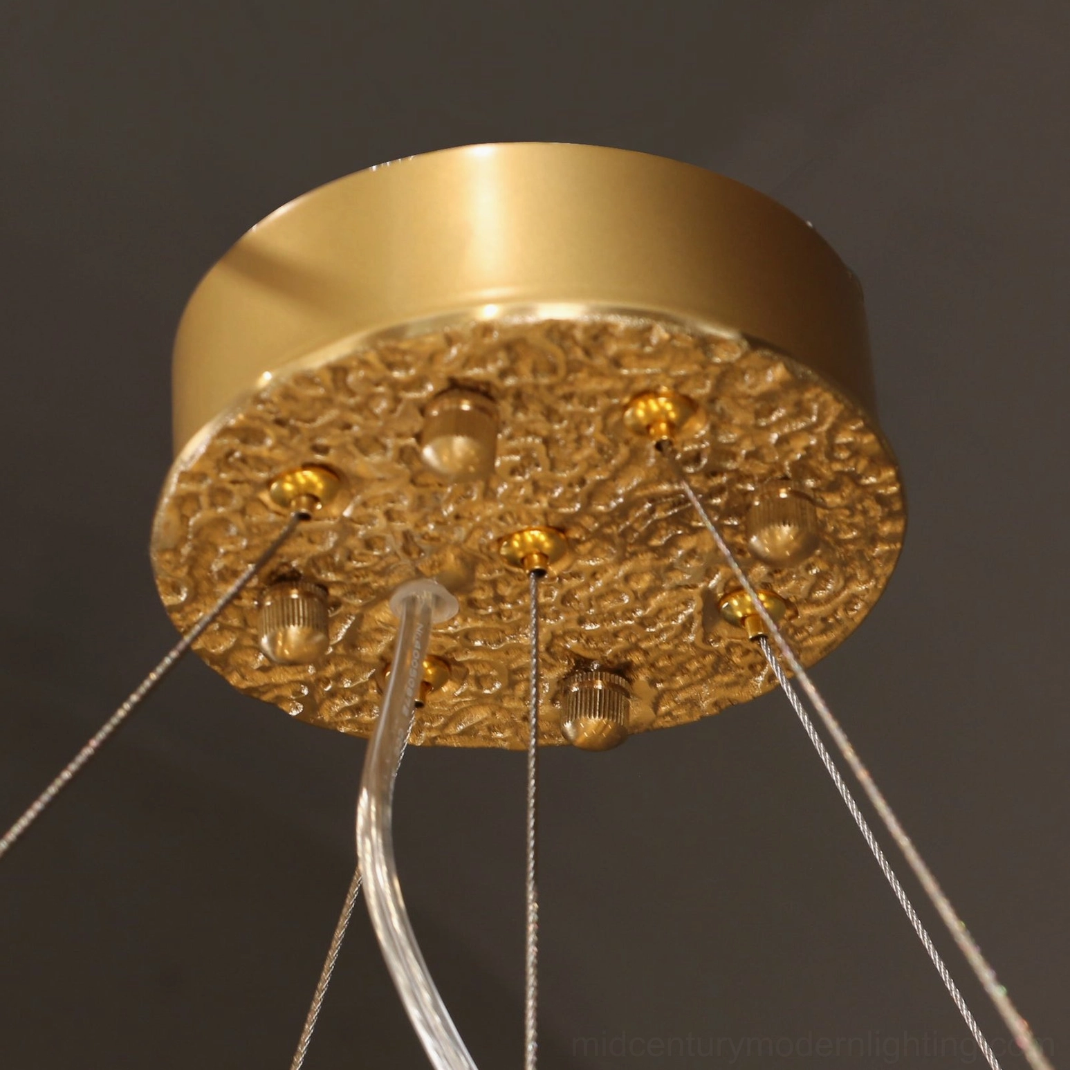 Brass ceiling mounting plate with decorative embossing and wire outlets detail close-up