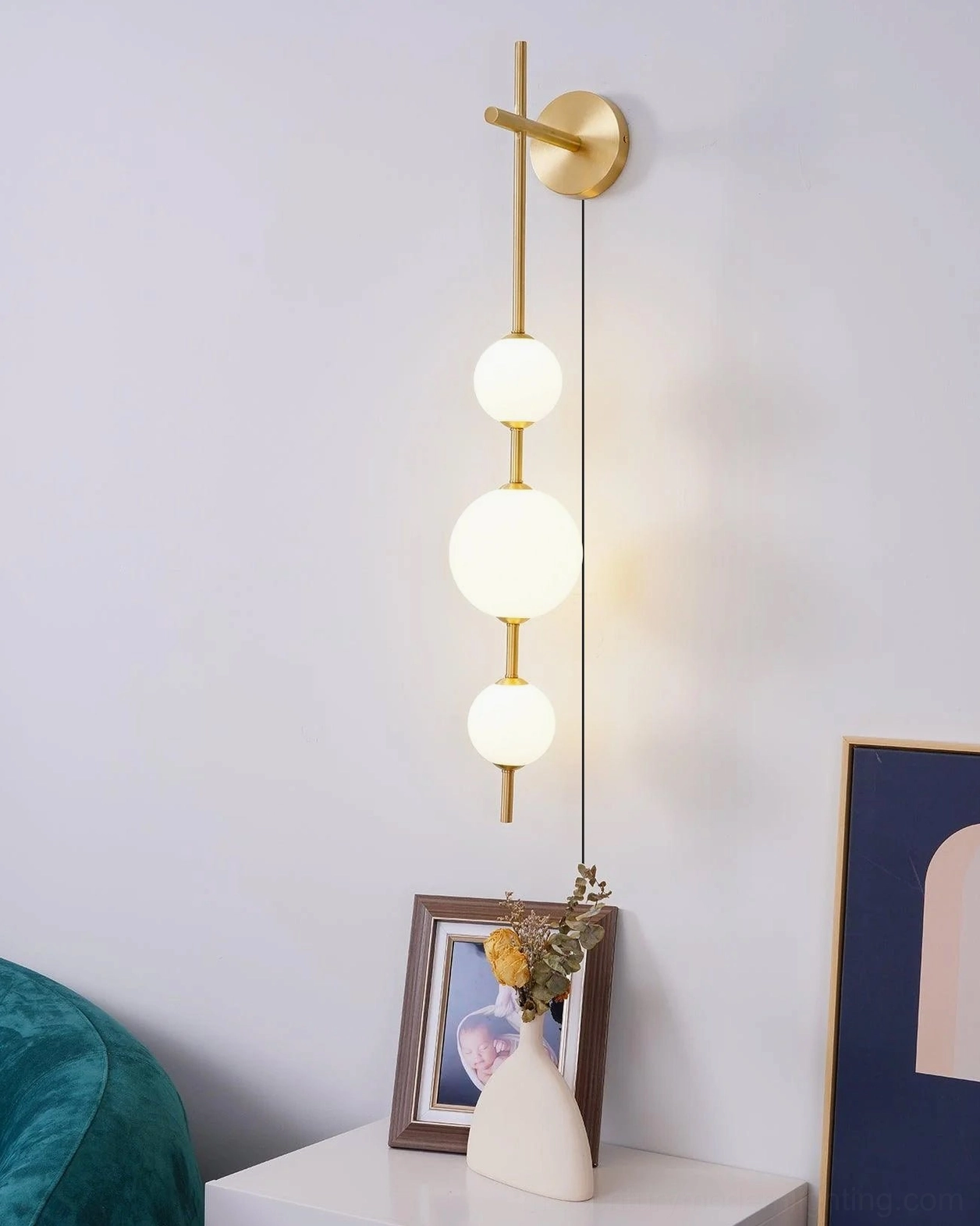 Brass vertical globe wall lamp installed in modern home corner setting with side table and decorative accents