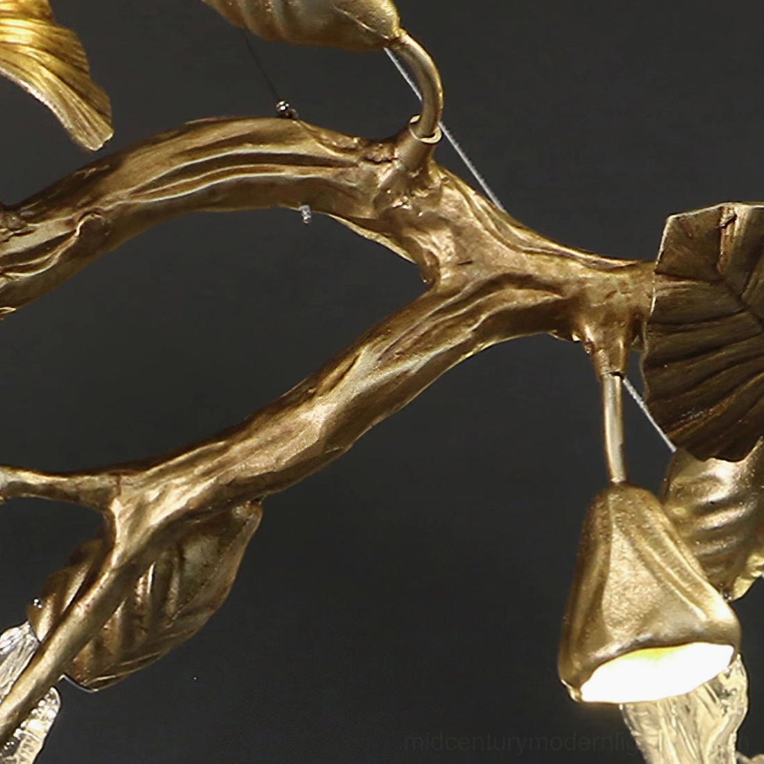 Close-up macro detail of brass leaf chandelier frame - polished gold metal branches with embossed leaf texture