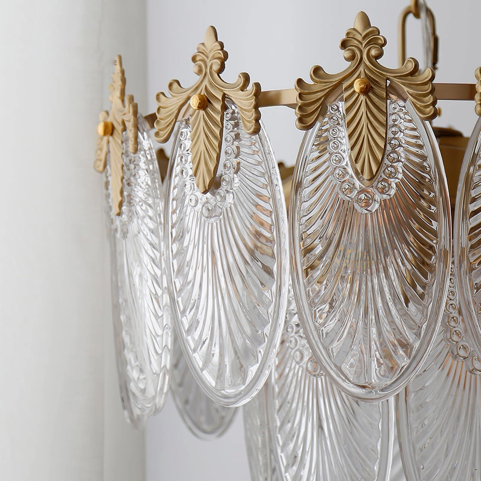Close-up side view of brass leaves chandelier showing embossed ribbed glass structure and decorative brass leaf mounts, polished gold finish