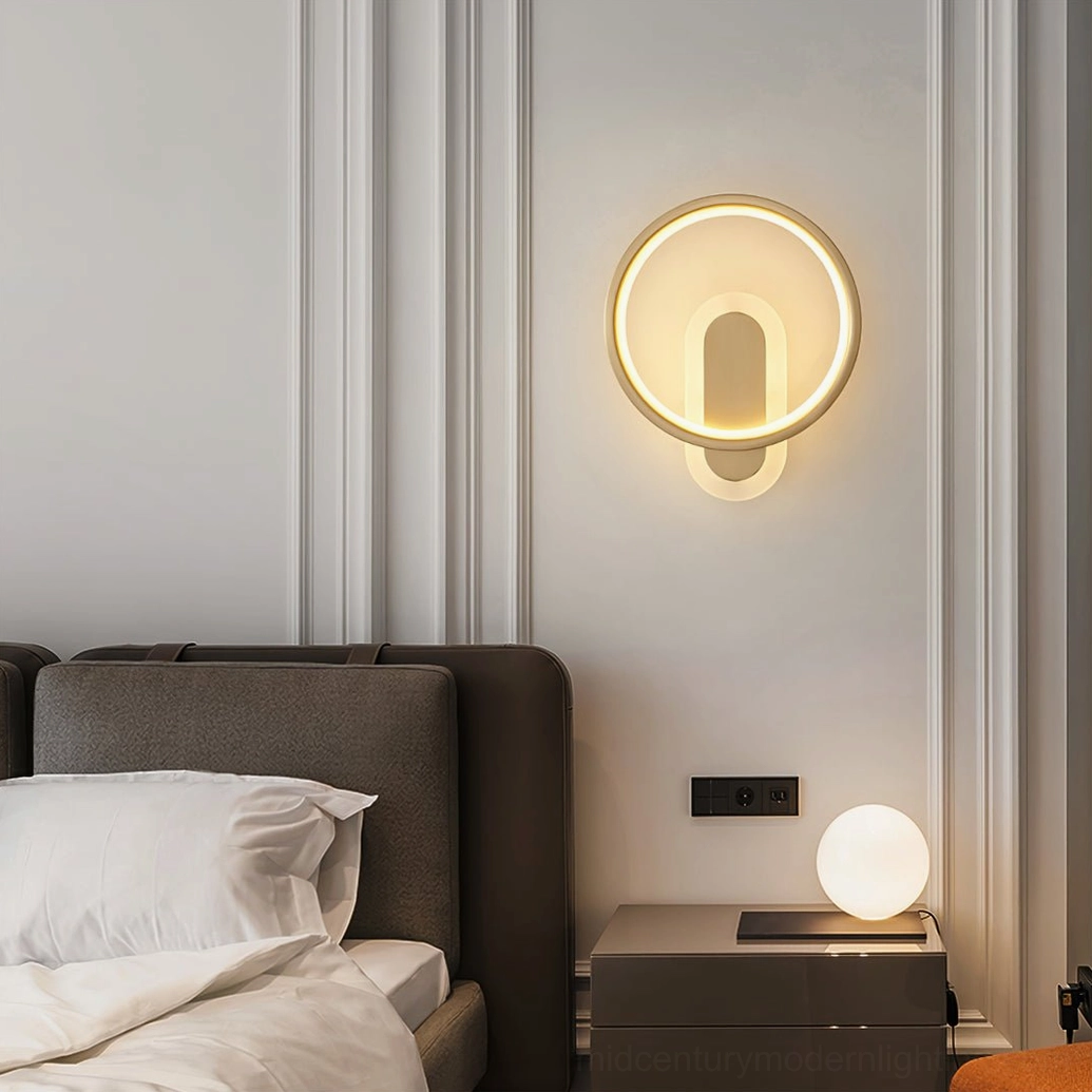 Modern brass wall sconce mounted in luxury bedroom with tufted headboard warm lighting