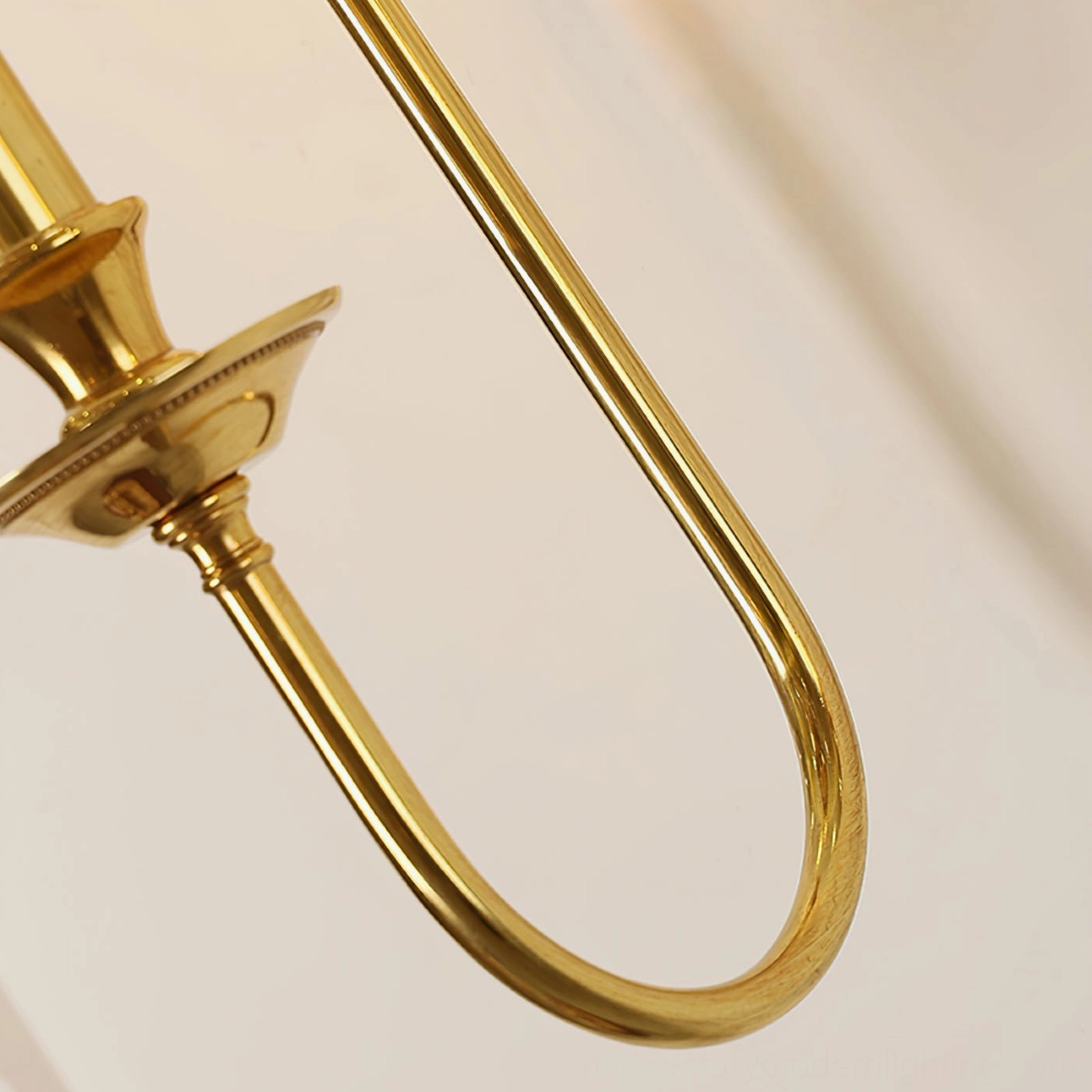 Detailed view of smooth U-shaped polished brass arm with beaded candlestick tray