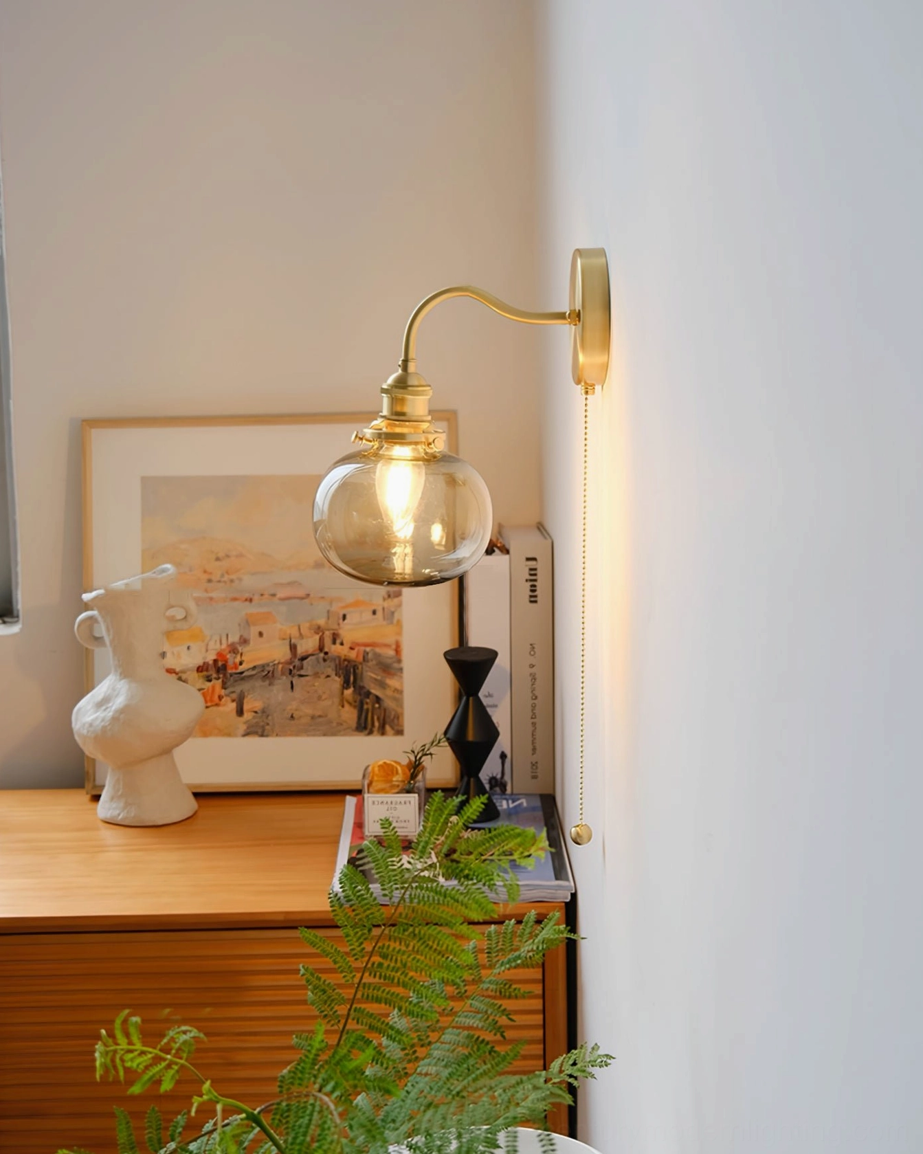 Warm vintage brass wall sconce beside wooden table with home décor - timeless mid-century aesthetic