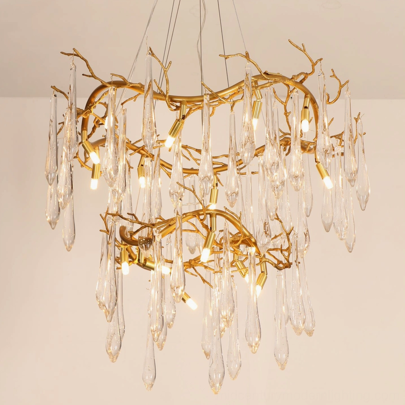 Detailed view of brass waterfall chandelier frame construction, polished gold metal branches, and suspended clear teardrop crystal glass decorations