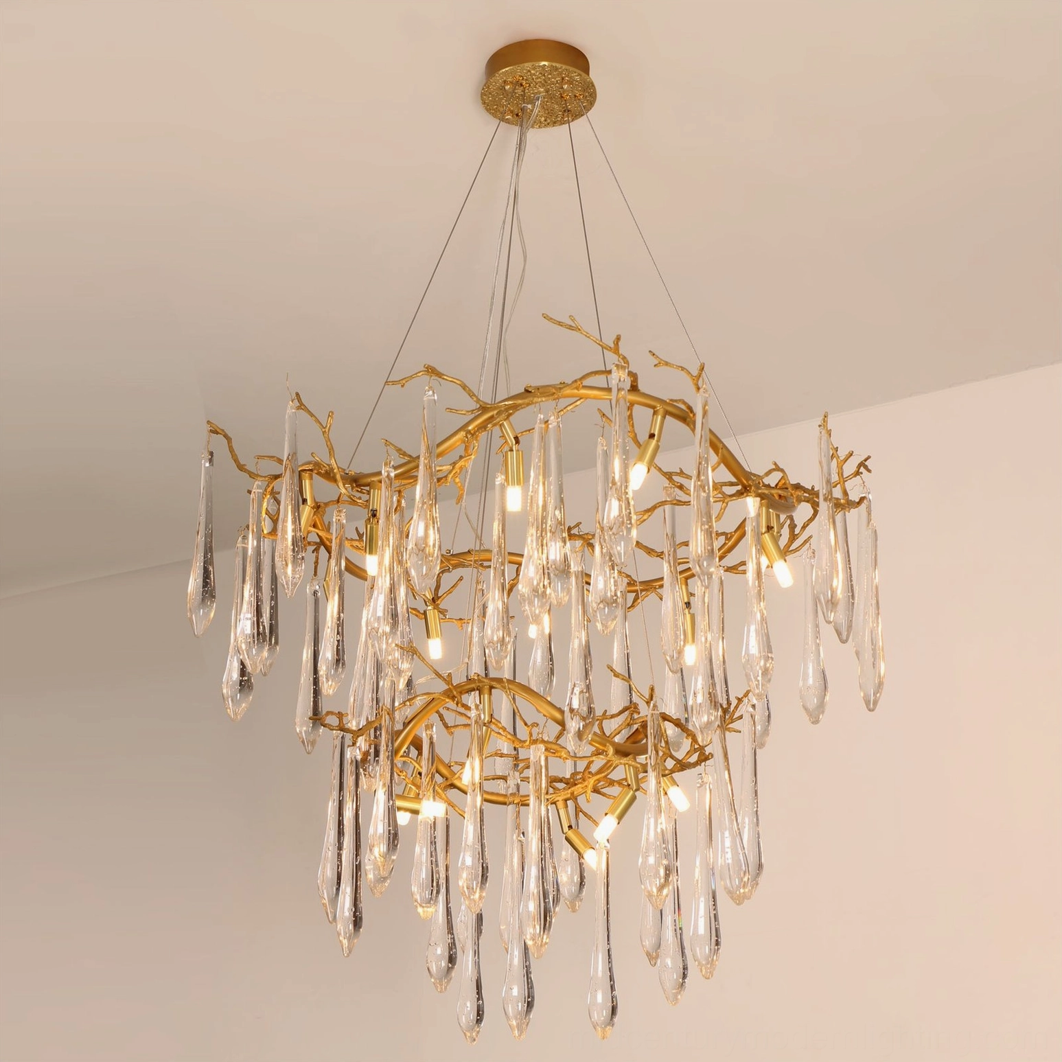 Overhead slanted view of brass waterfall chandelier highlighting polished gold finish and suspended teardrop crystal glass decorations