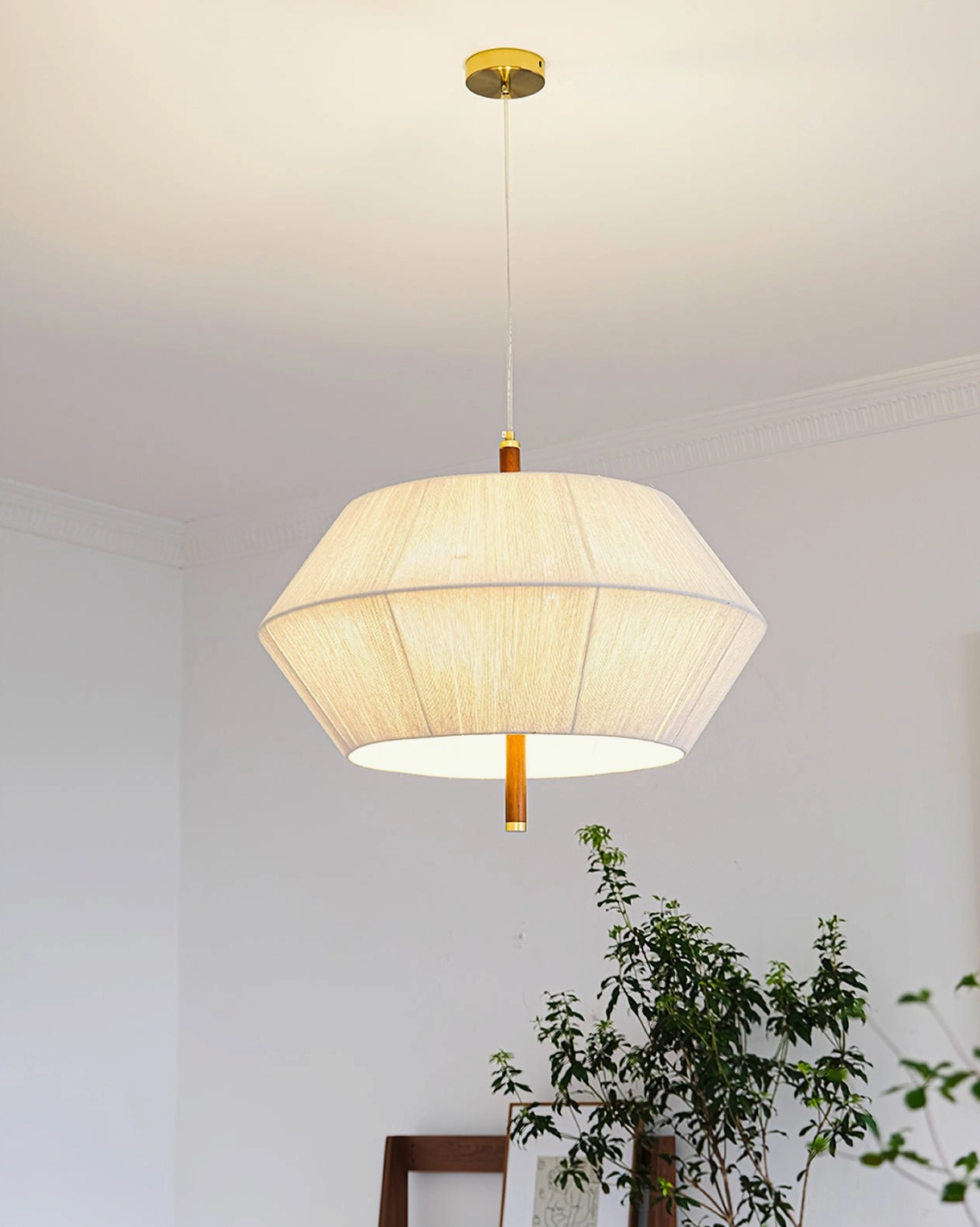 Illuminated Brera pendant lamp casting warm soft light from brass ceiling fitting in residential space