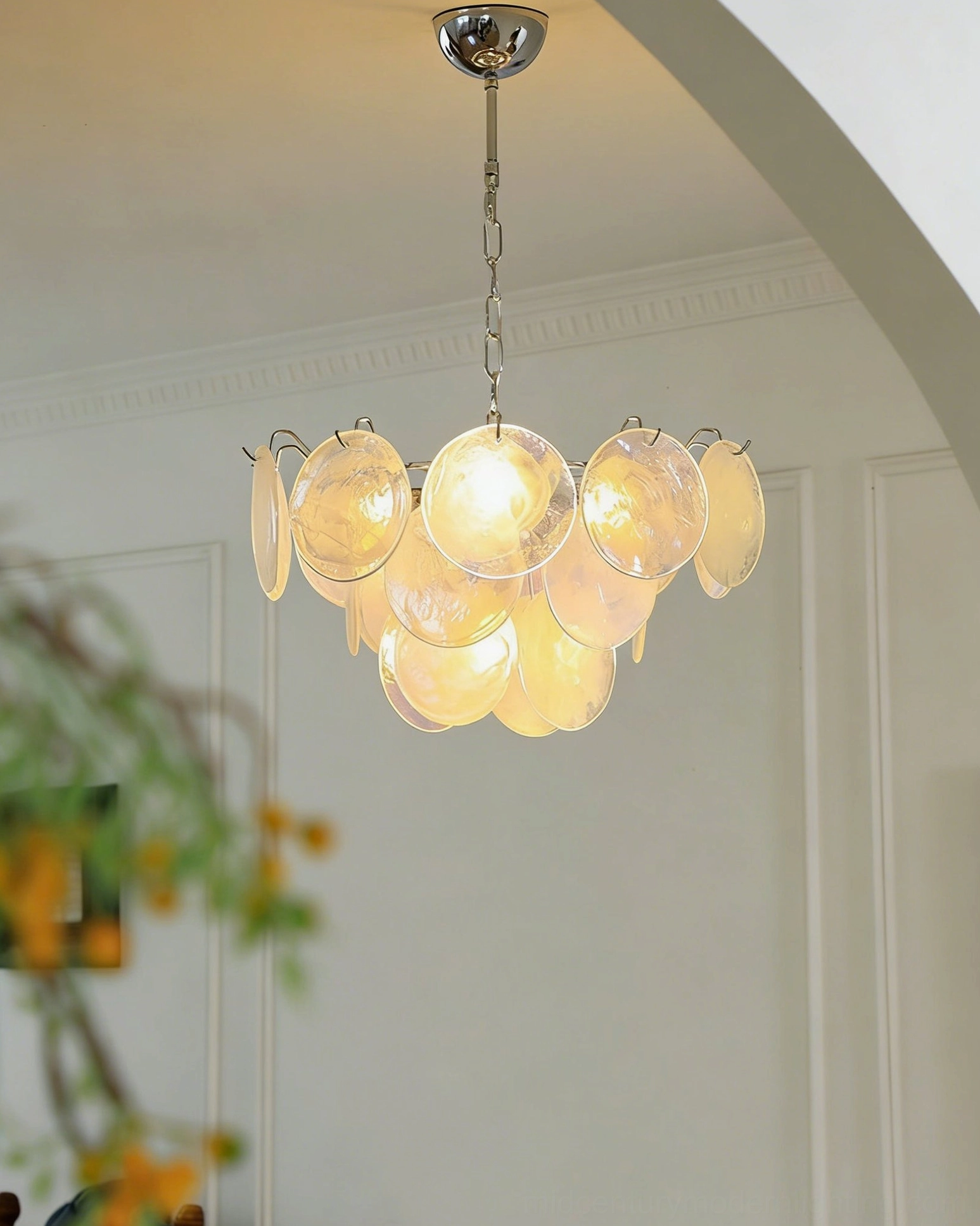 Brette amber glass disk chandelier low front angle view in minimalist white room showing cozy luxury warm lighting