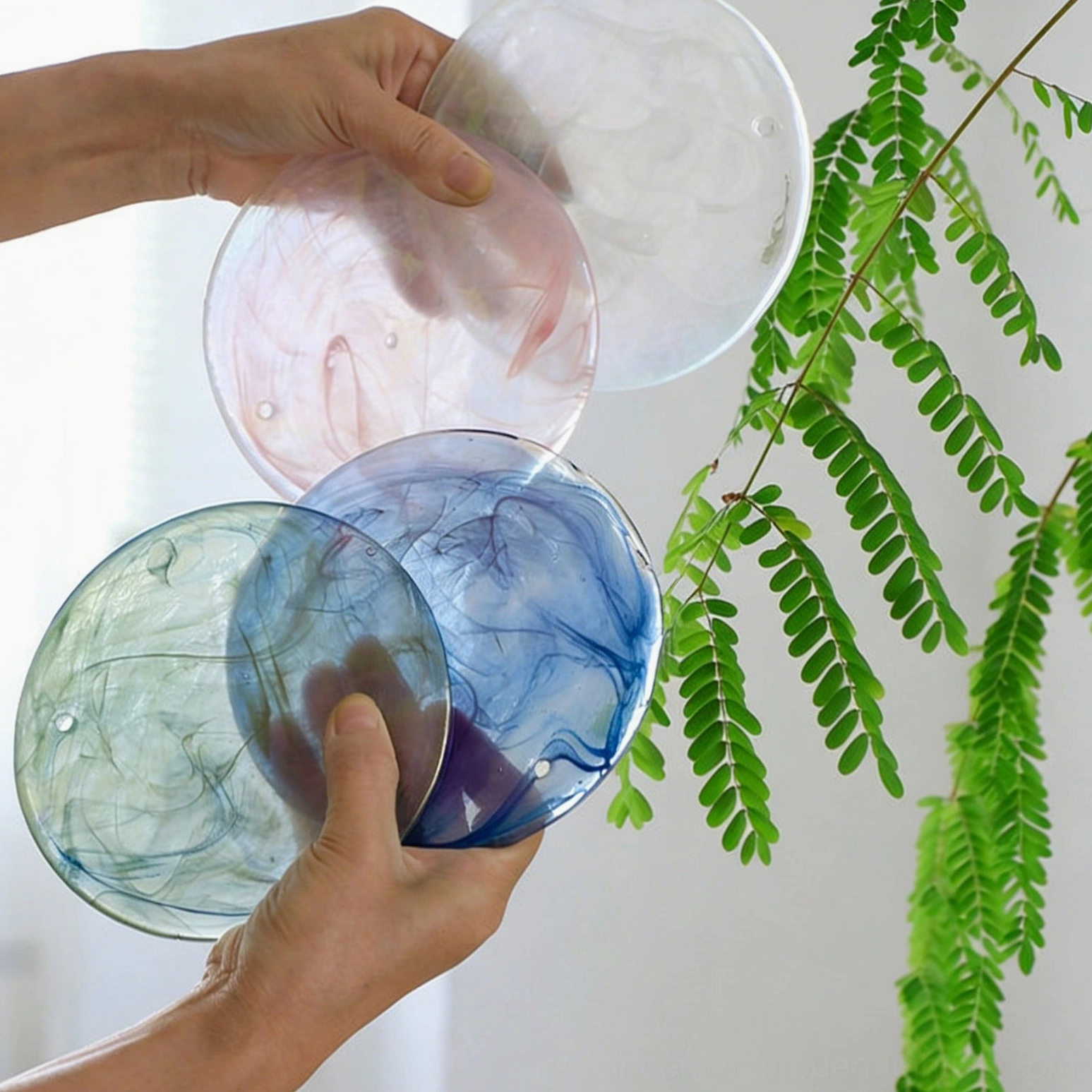 Close-up detail of Brette marbled glass discs showing iridescent pink blue and green color variations with fern plant styling