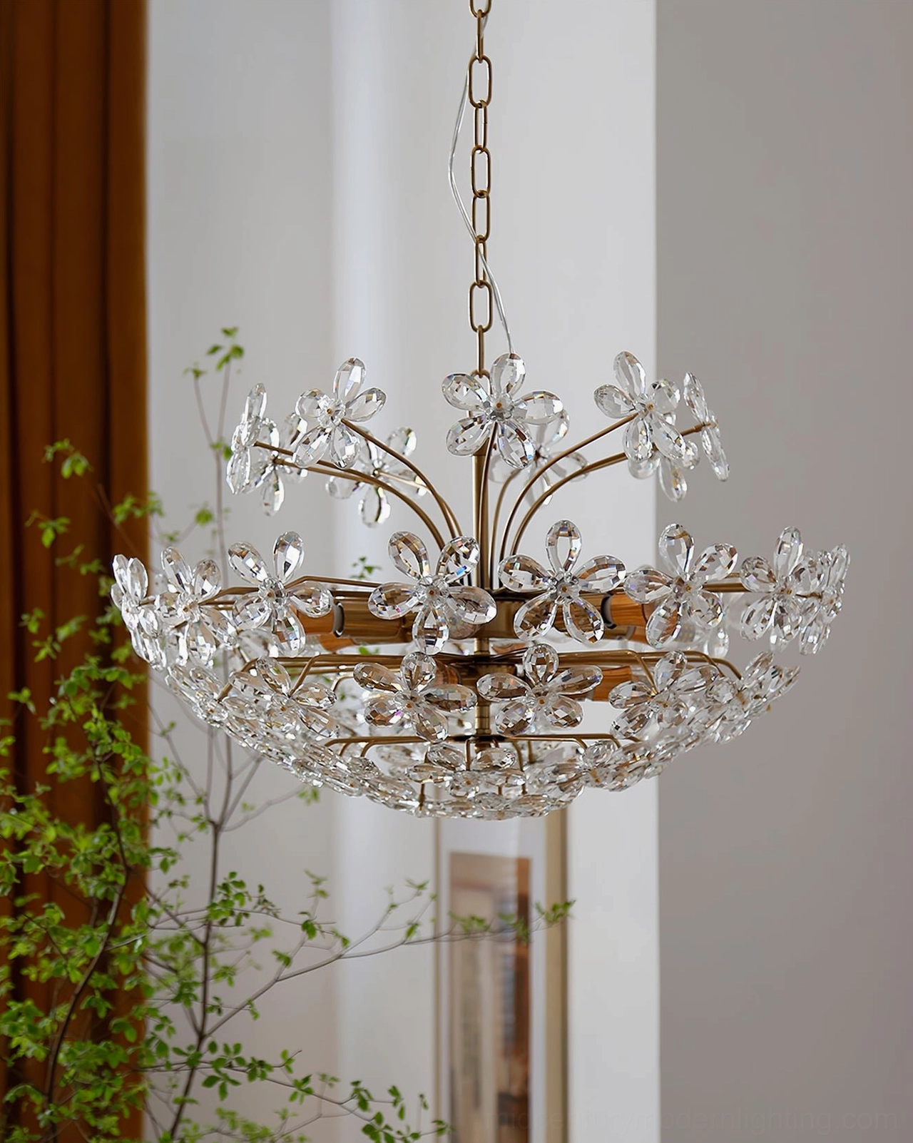 Clear crystal floral chandelier hanging in living room with green plants and brown curtains, fresh romantic vintage lighting