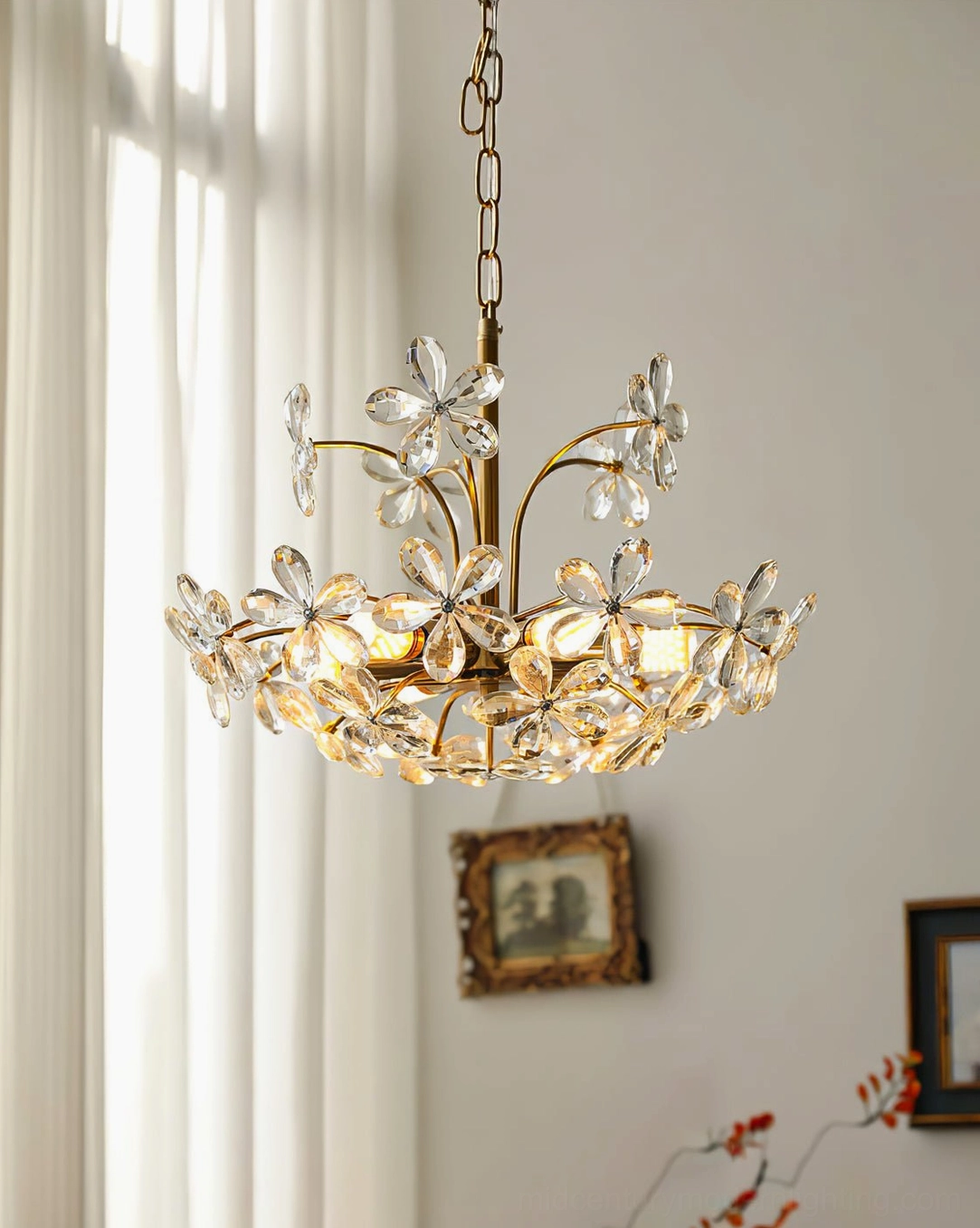 Gold floral crystal chandelier in sunlit living room with sheer curtains, warm vintage accent lighting installation