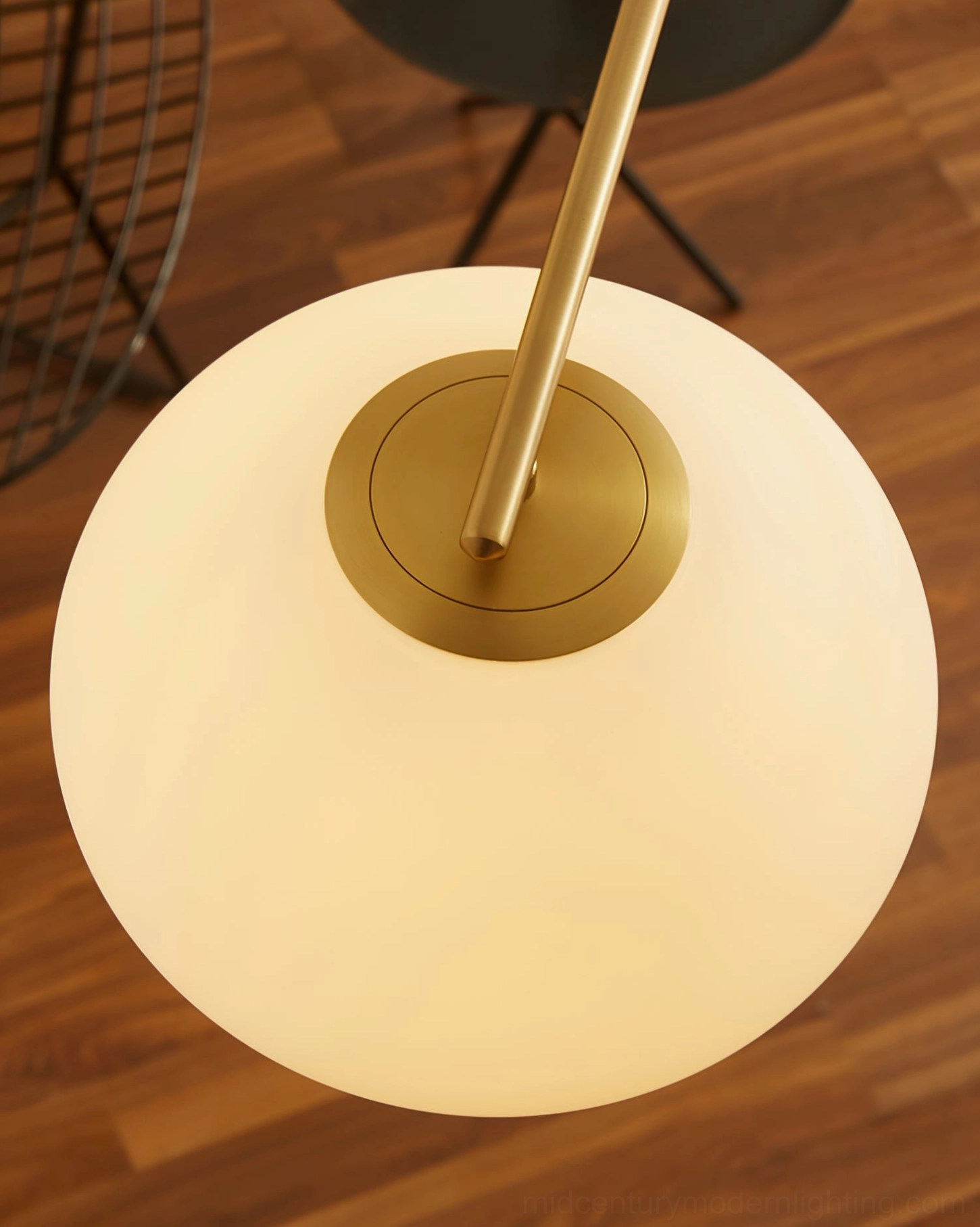 Bottom-up view of illuminated Briette ceiling lamp showing frosted glass globe and brass gold hardware with warm light emission