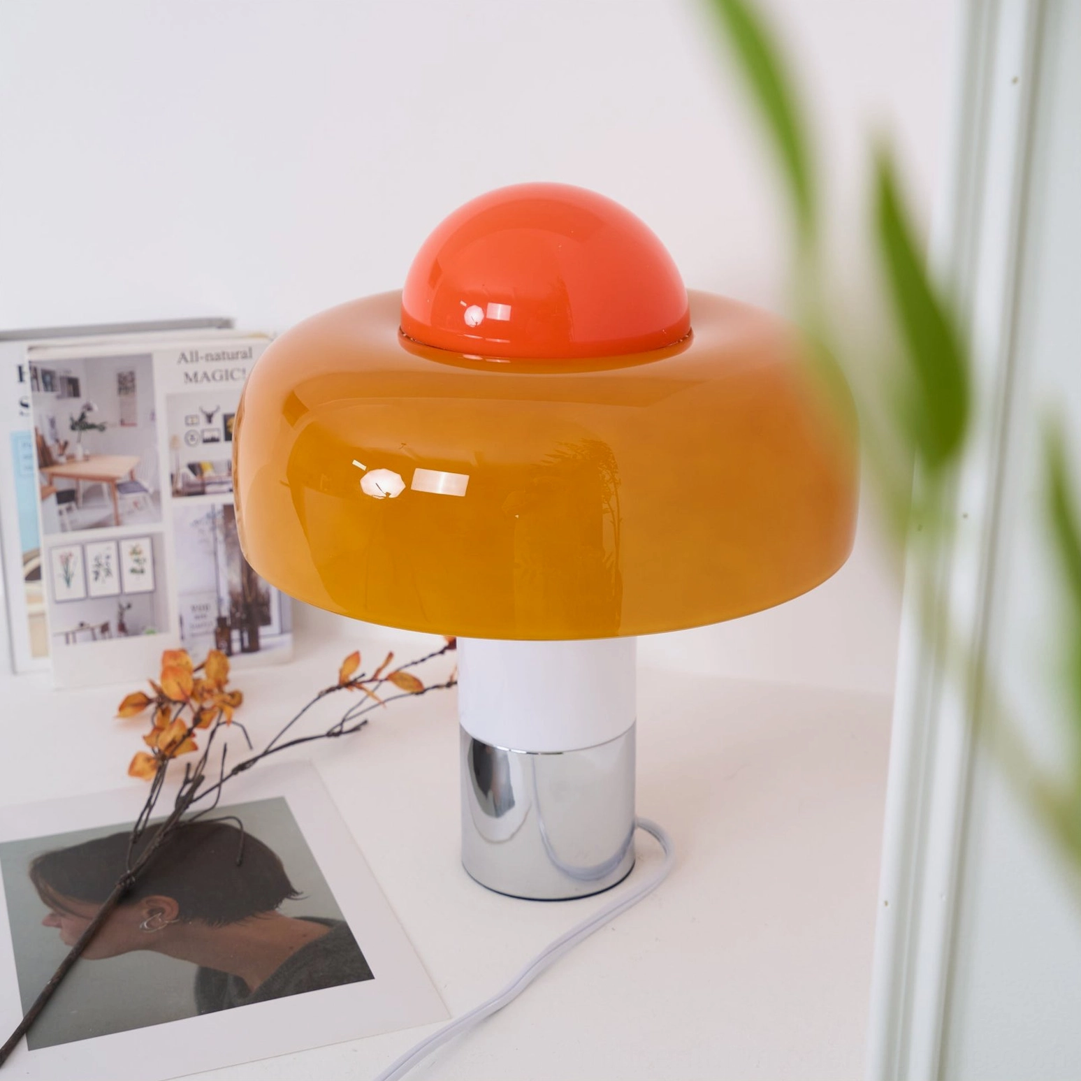 Brumbry lamp close-up showing red finial accent and polished chrome hardware on tabletop with magazine