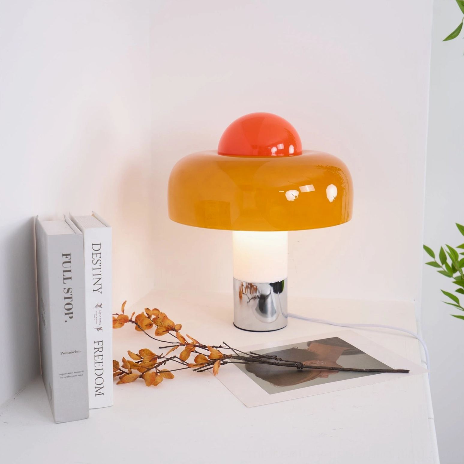 Brumbry lamp centered on white corner table with stacked neutral-toned books, mid-century aesthetic