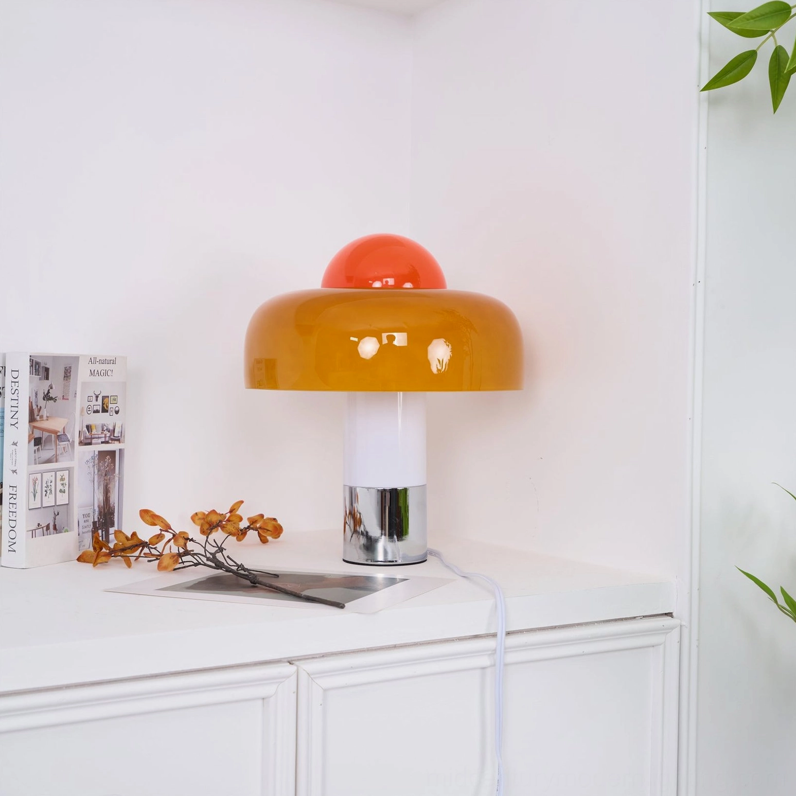 Brumbry table lamp rear three-quarter view in bright minimalist room with dresser styling and florals