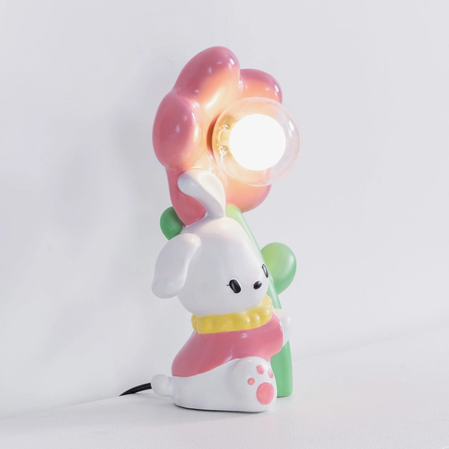Back view of lit Bunny Flower Table Lamp with visible power cord and pink floral illumination