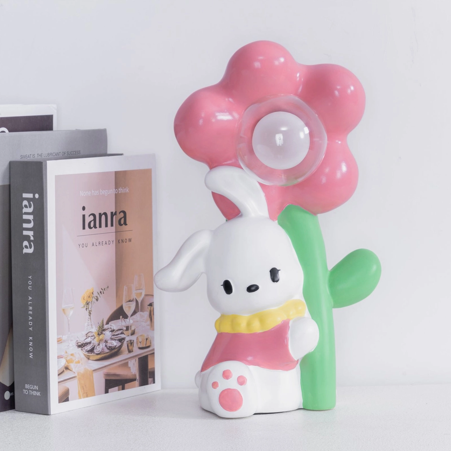 Unlit Bunny Flower Table Lamp on desktop with decorative books and pink shade styling
