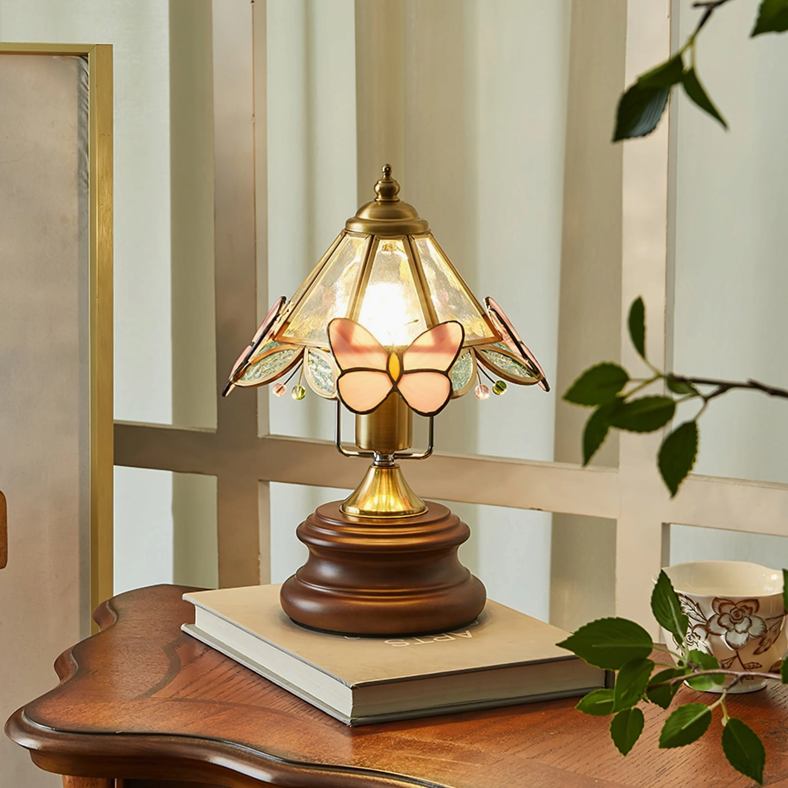 Jenny Butterfly Table Lamp displayed on rustic wooden side table with decorative books and potted plants, vintage home decor styling