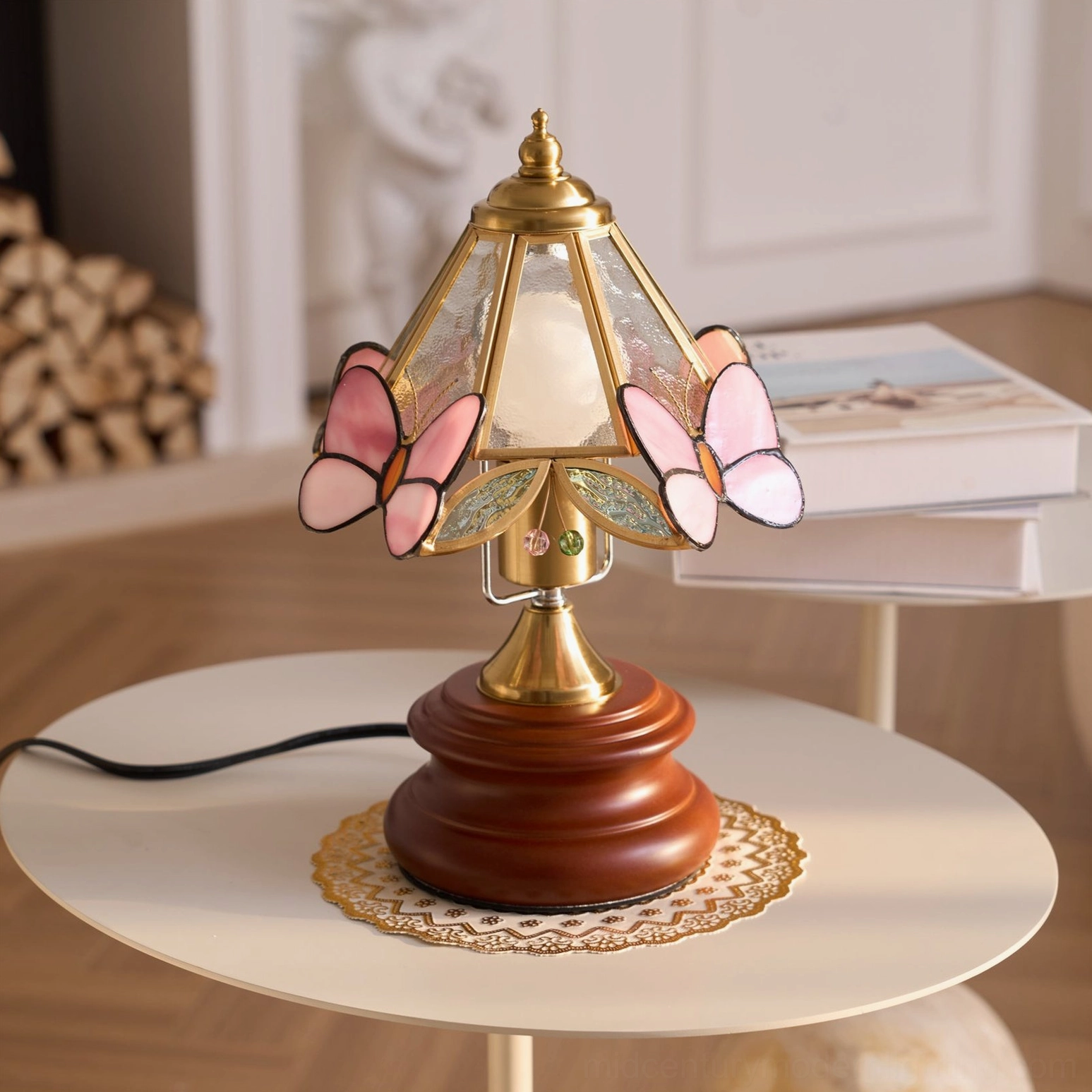 Side angle view of Jenny Butterfly lamp with four pink butterfly accents on shade, displayed near firewood stack home interior